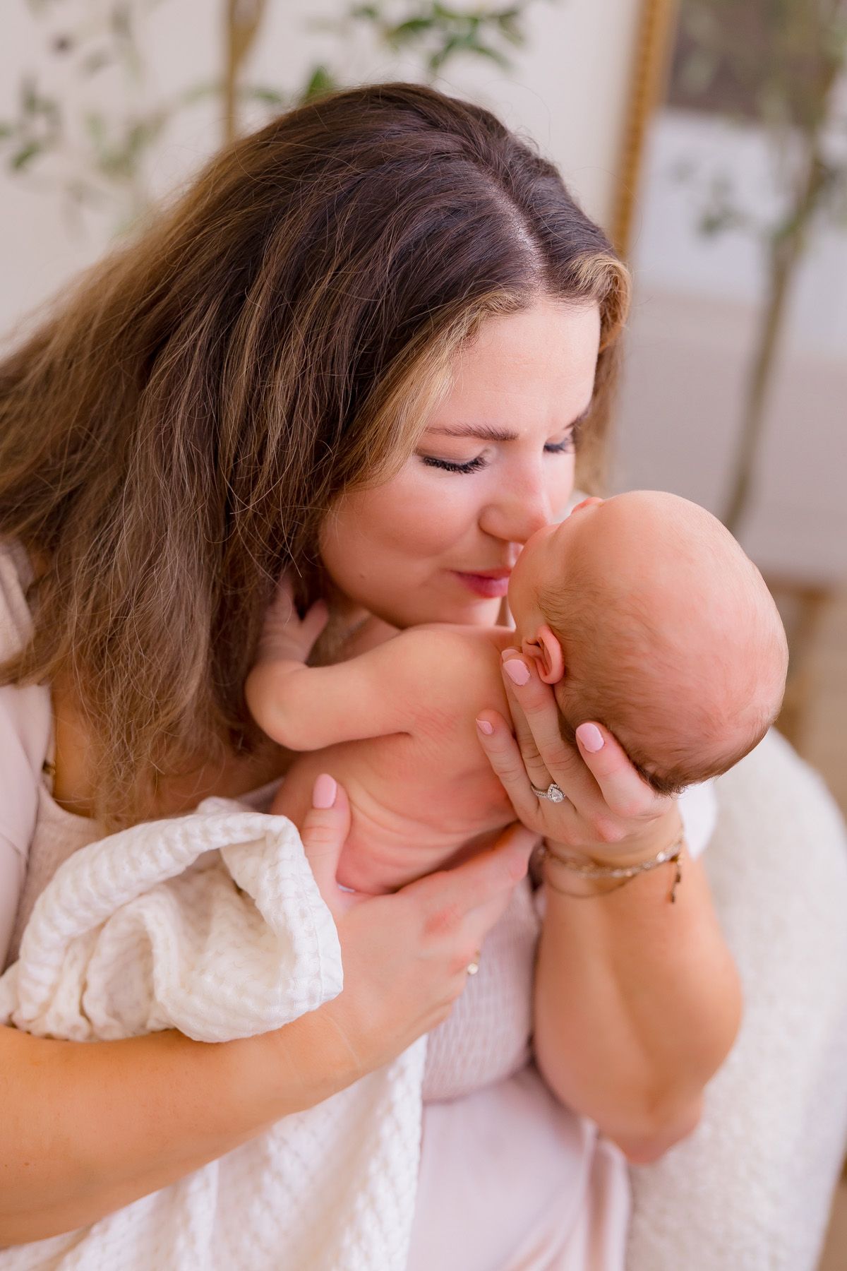Tender moment between mother and newborn baby in soft natural window light.