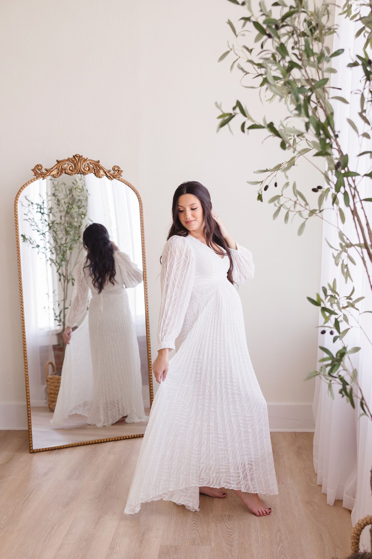 Ethereal indoor portraits with flowing white dress and ornate mirror in minimalist space.