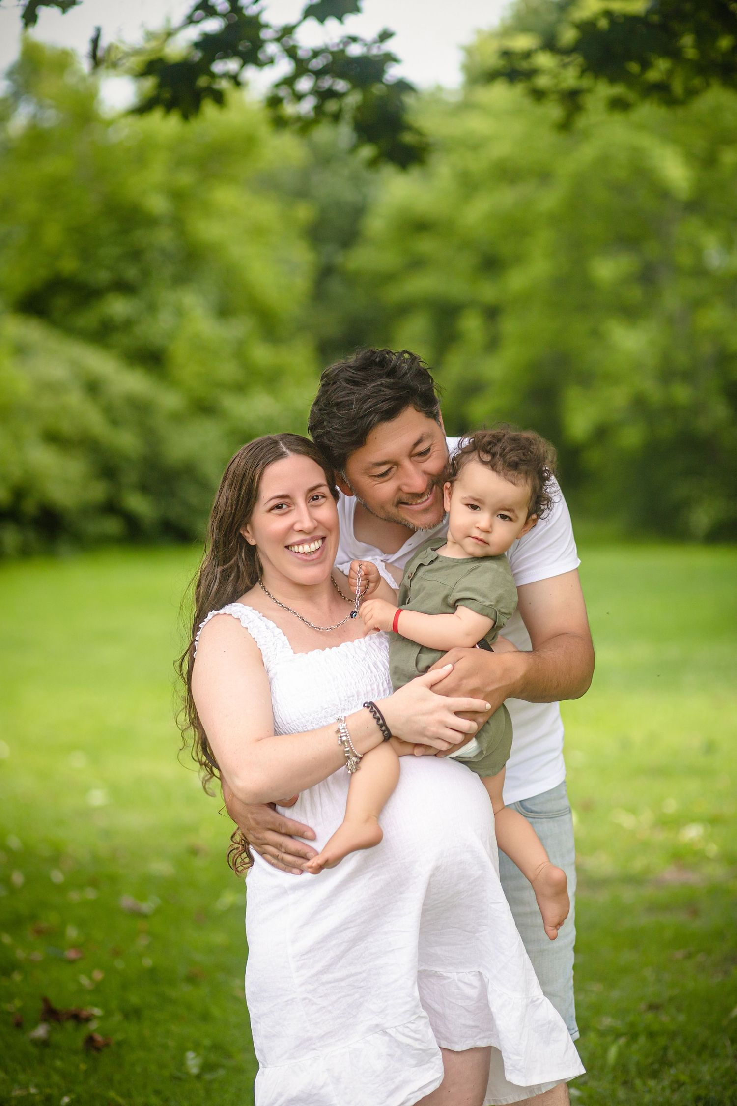 Happy posing outdoors in a lush green park. Maternity photo session at local park in Kingston, Ontario, with maternity photographer.