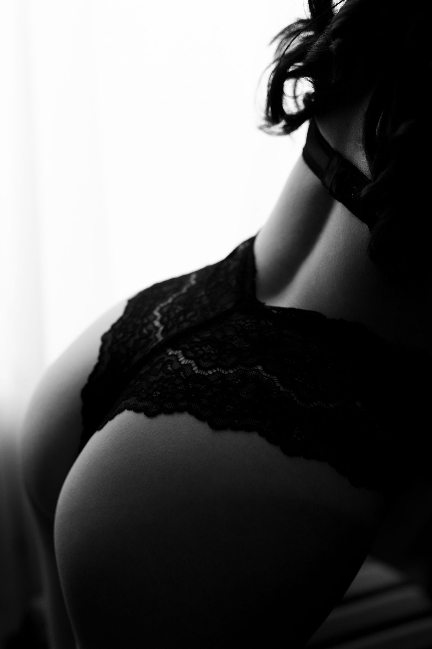 Silhouette portrait of a person wearing lace against a stark white background.