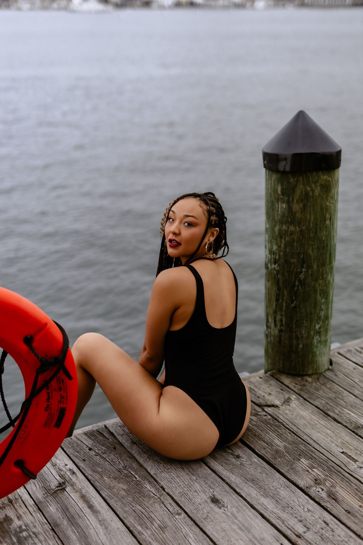 A series of photos showing someone in a black swimsuit and red life vest posing on a wooden dock by the water in downtown Annapolis.