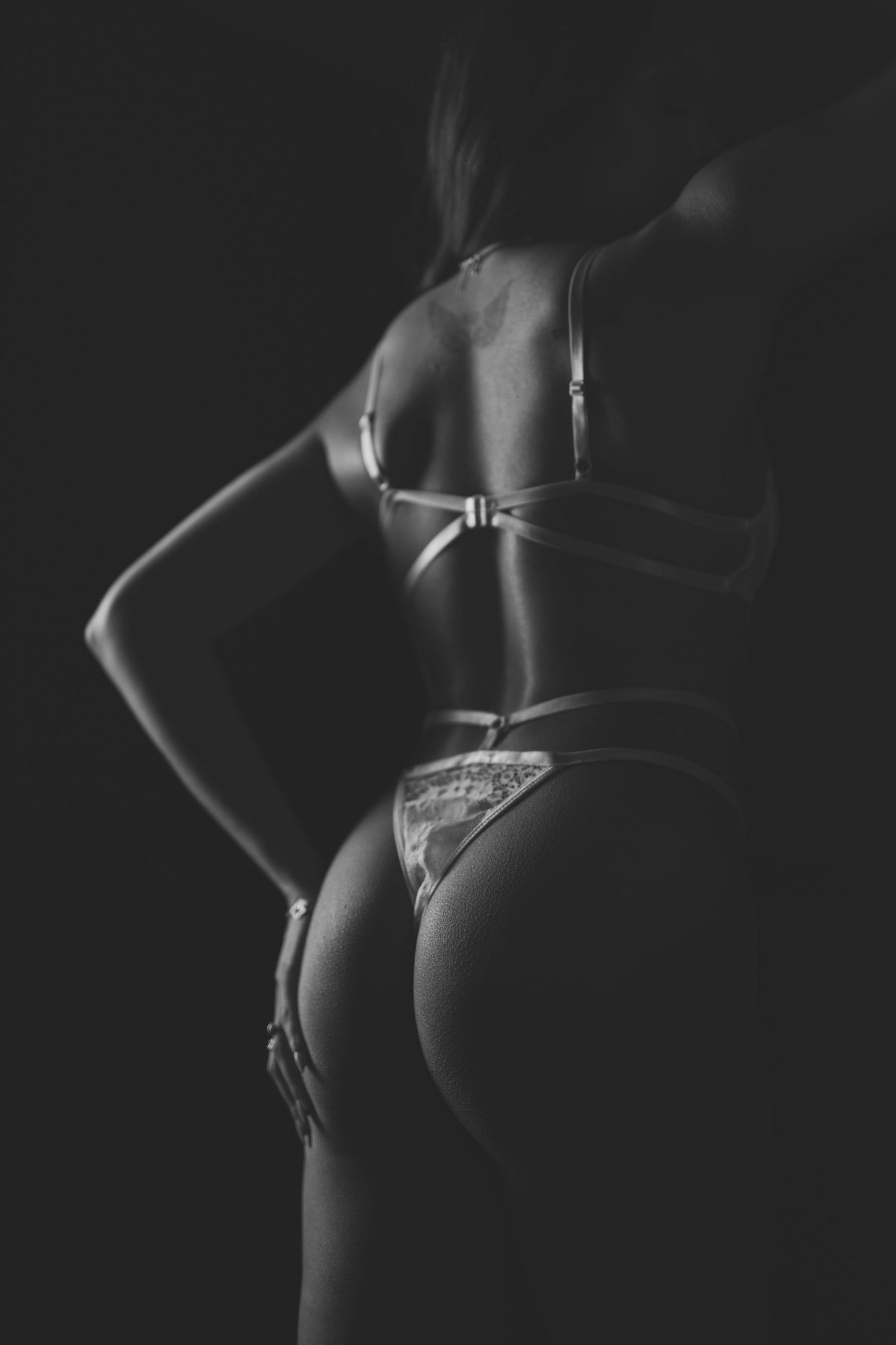Artistic black and white photo series showing silhouetted feminine figure in lingerie against dark background.