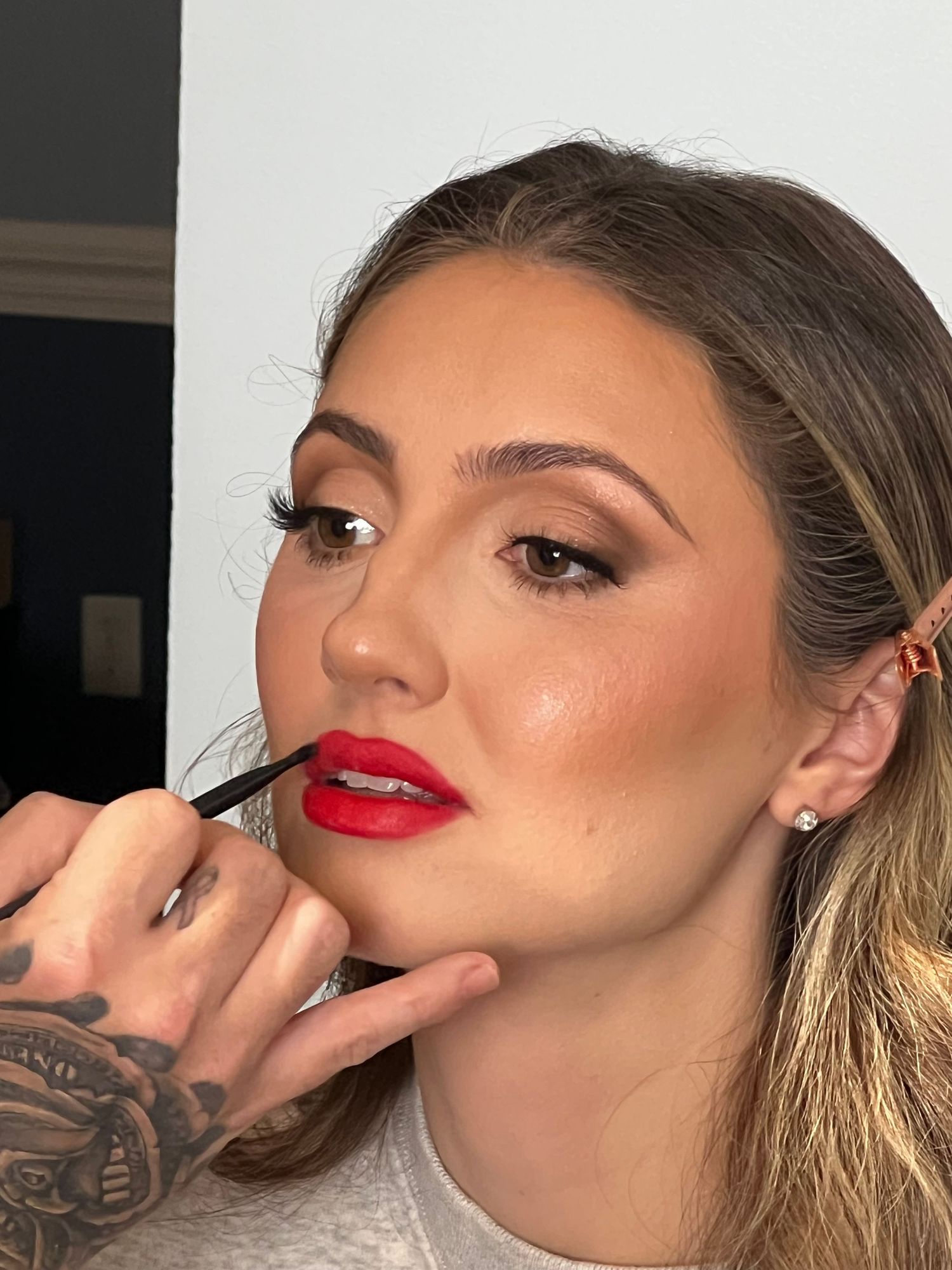 A person with red lipstick and brown hair getting hair and makeup done.