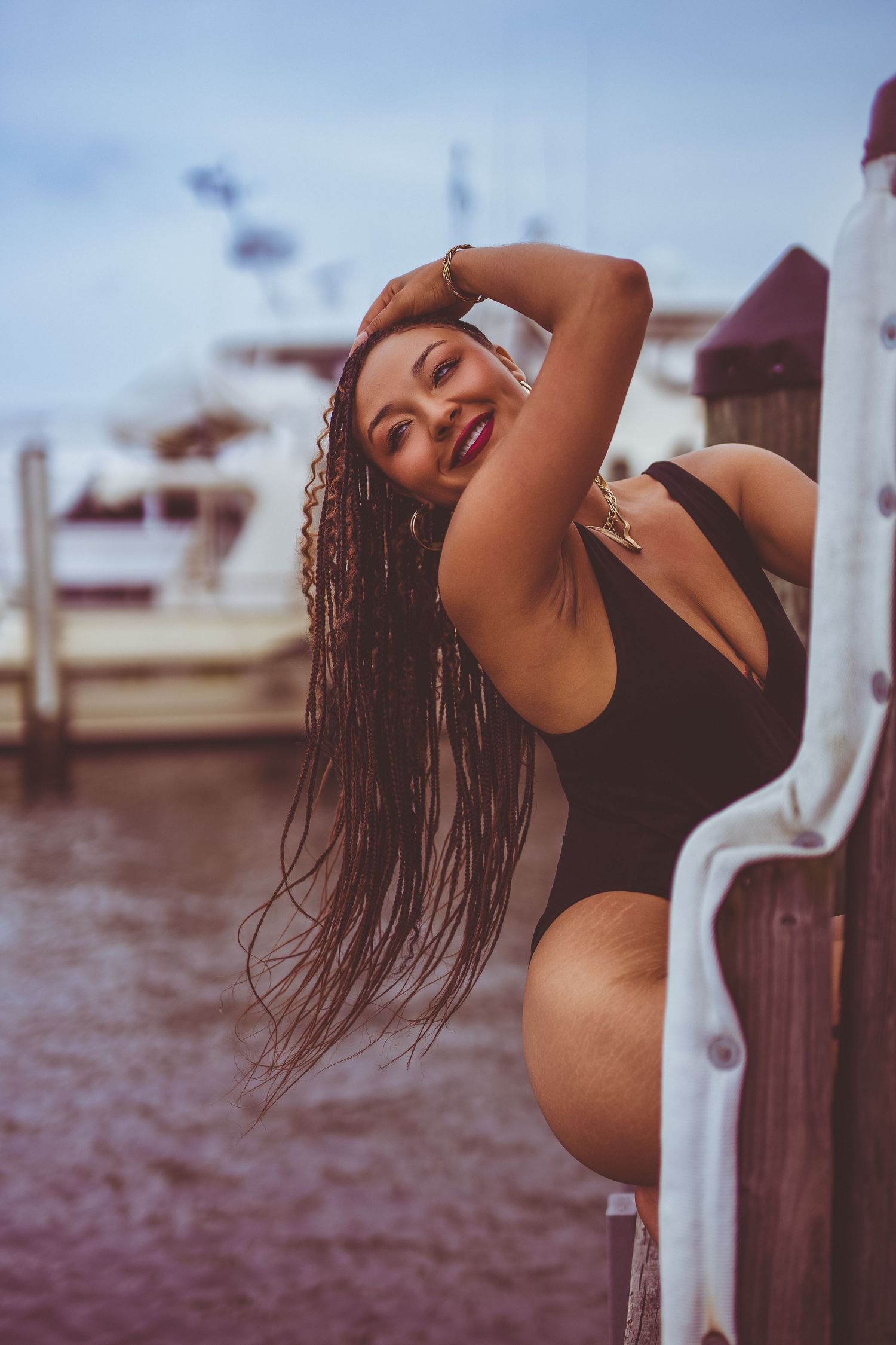 Woman in black swimsuit poses expressively near water during golden hour sunset photoshoot in Annapolis.
