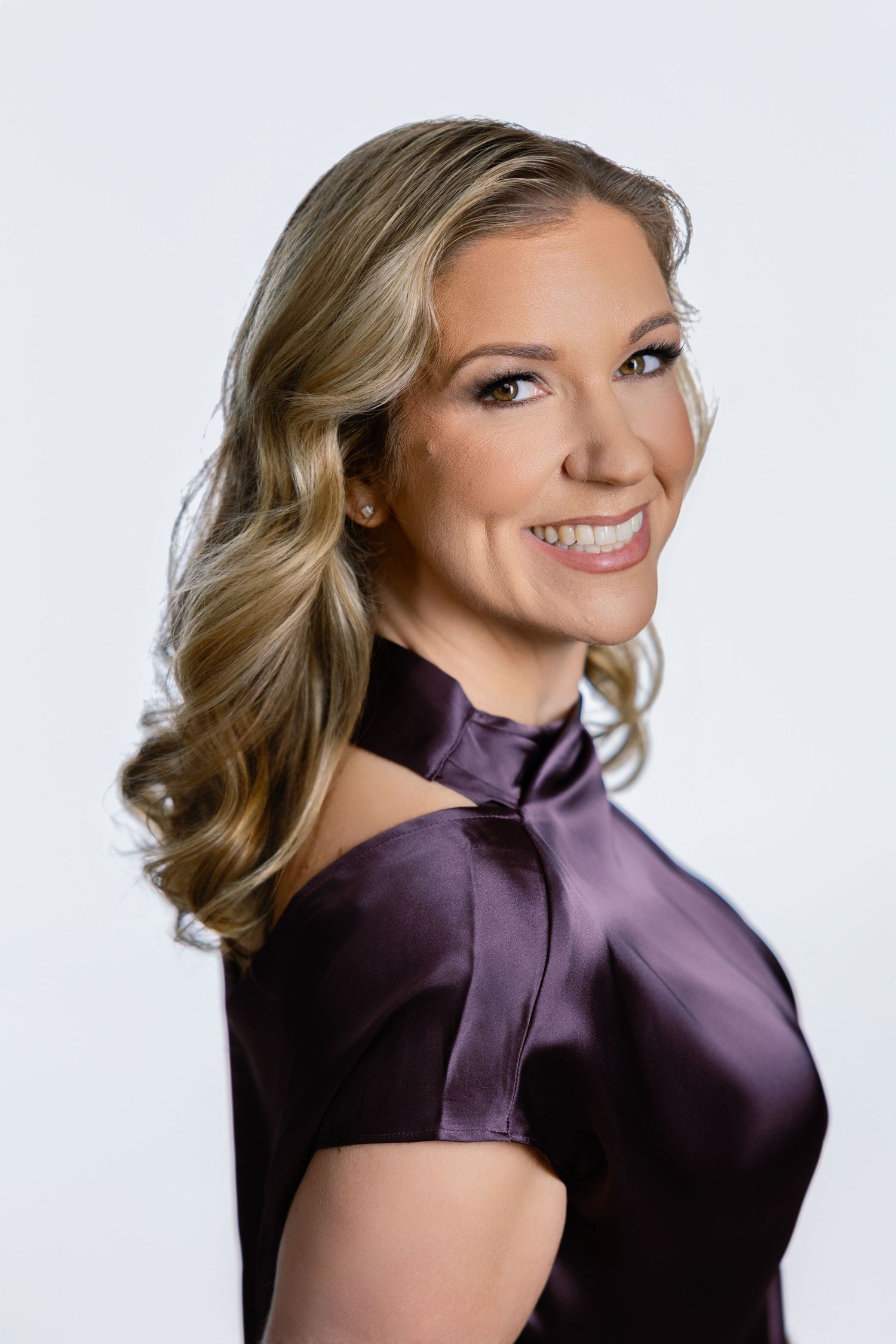Professional headshot of Laura, photographer at LD Photography wearing a purple satin blouse with short sleeves and a high neckline.