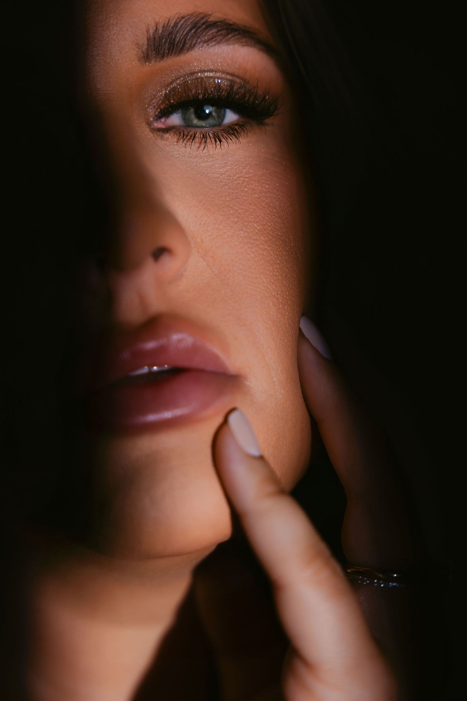 Close-up beauty shots of glossy lips and dramatic eye makeup in a dark, moody lighting setup.