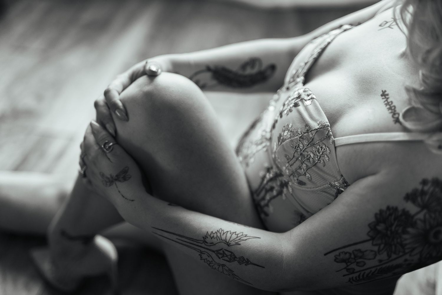 Black and white artistic boudoir photograph showing delicate lace lingerie details in soft lighting.