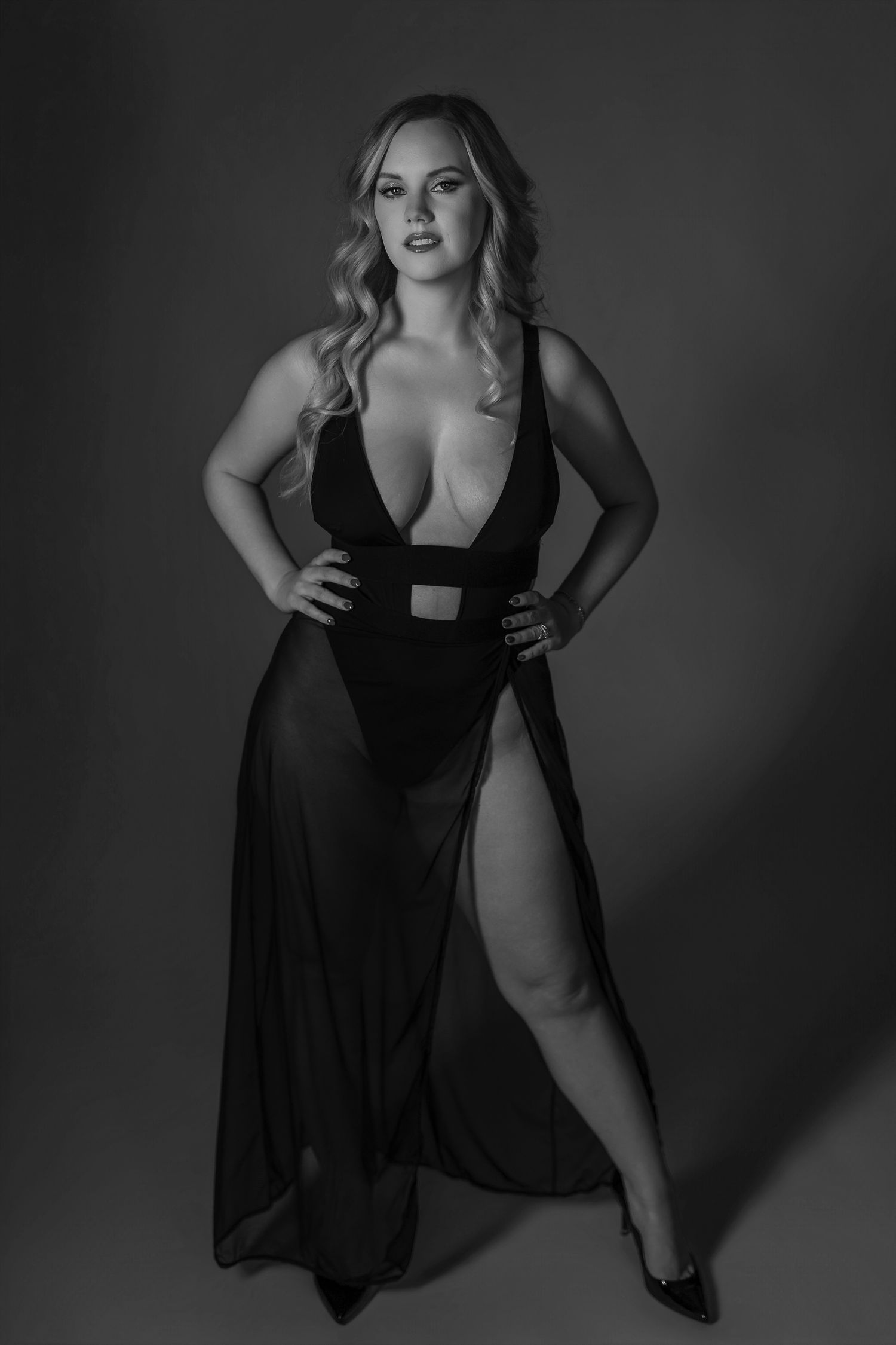 Artistic black and white boudoir portrait in flowing black dress against dark background in Maryland boudoir studio.