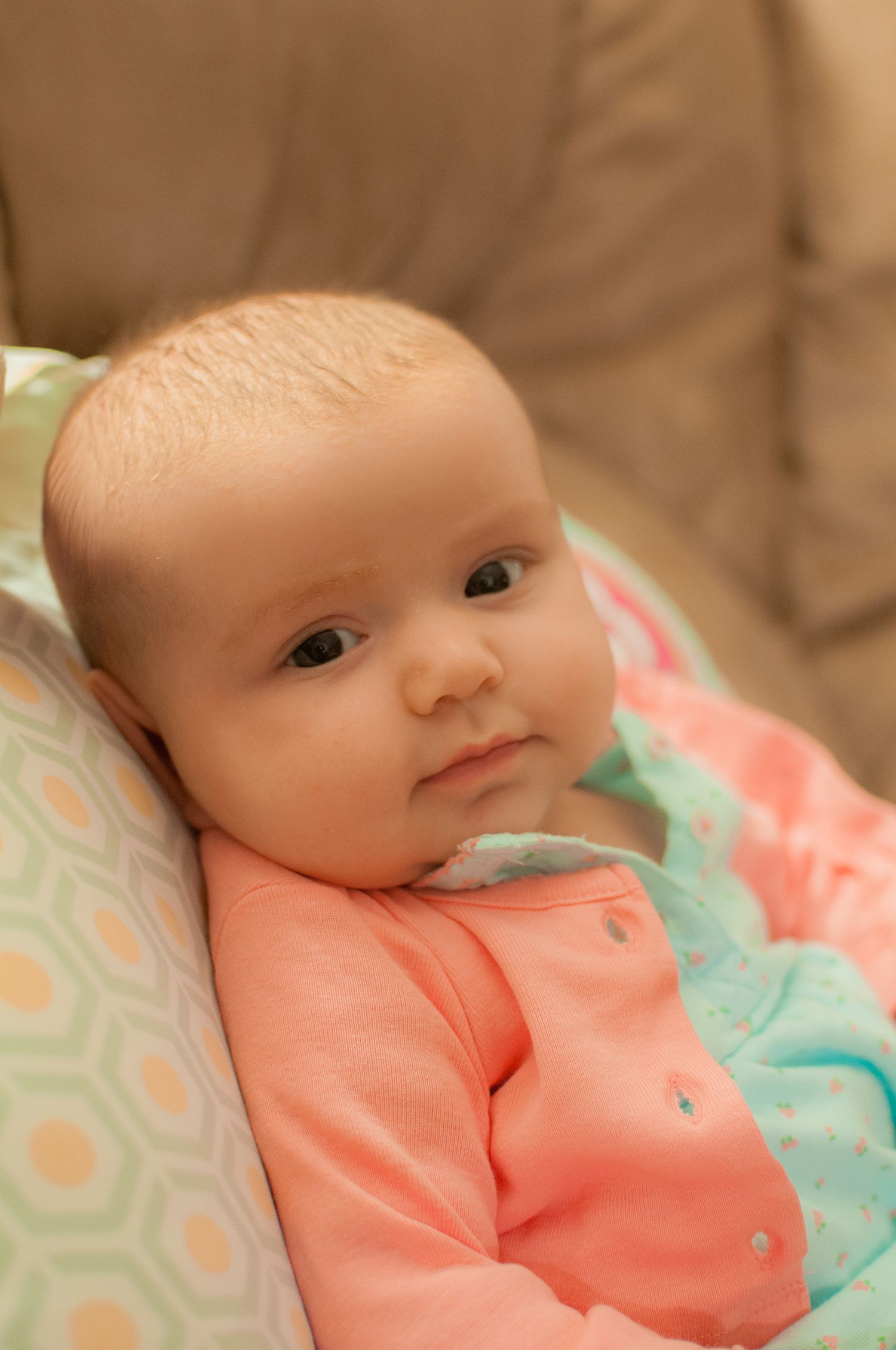 An infant wearing a pastel spring outfit chilling on a boppy.
