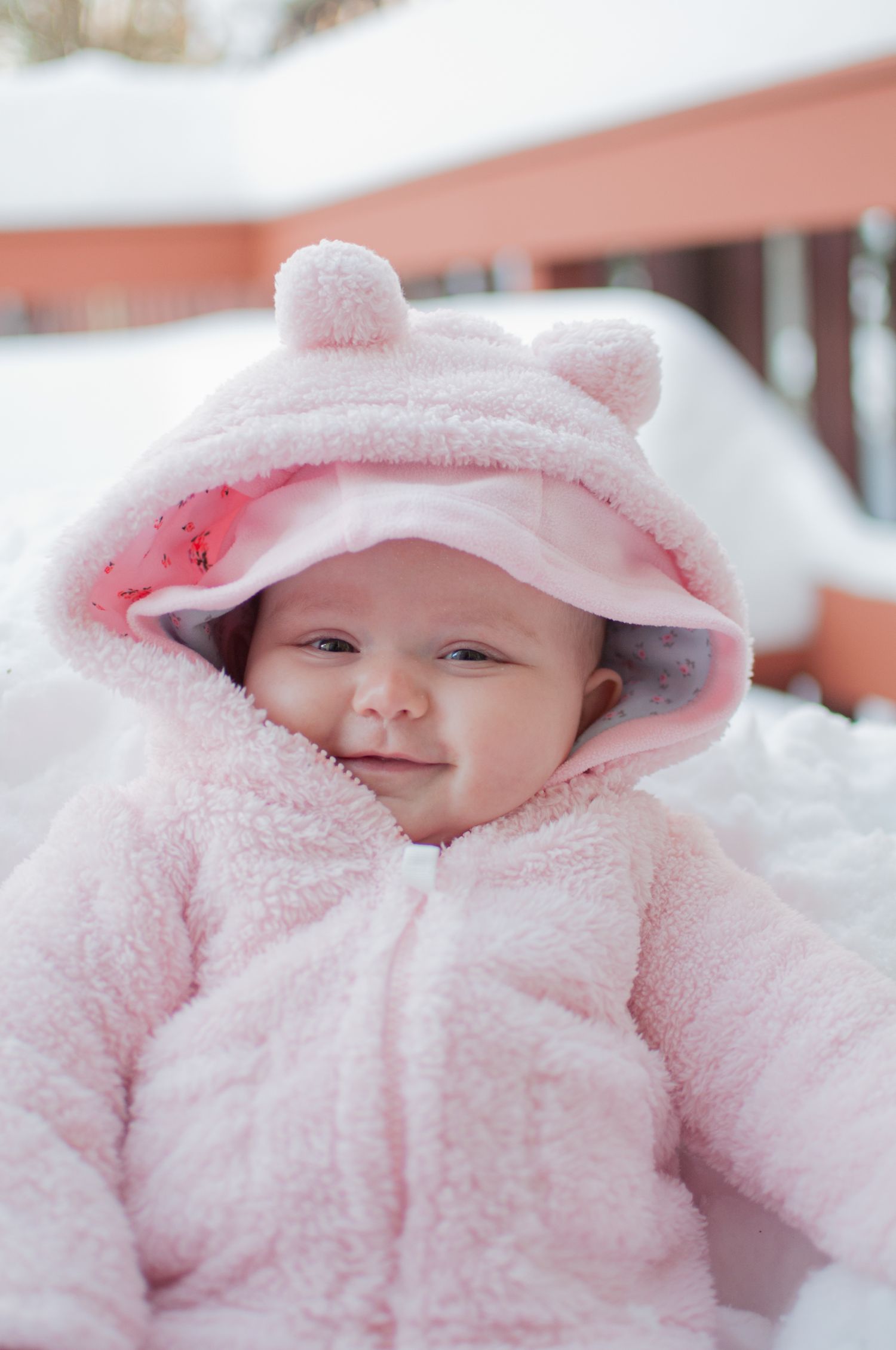 Portrait of smiling a baby wearing a soft pink coat in the snow