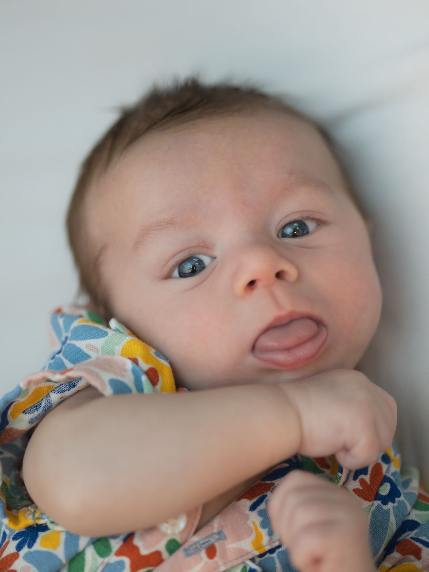 Portrait of a baby with blue eyes sticking out its tongue