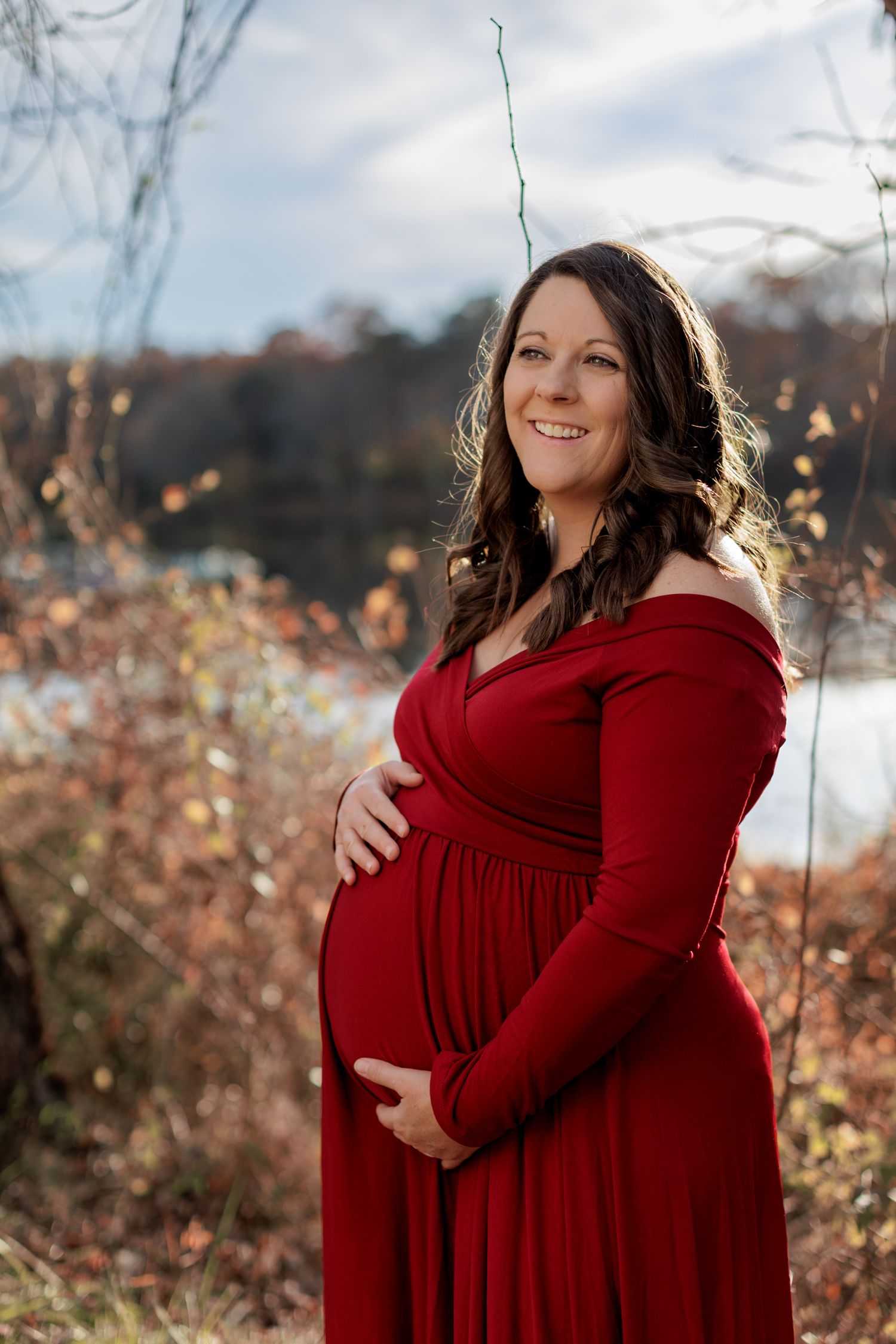 A pregnant woman in a deep red dress holds