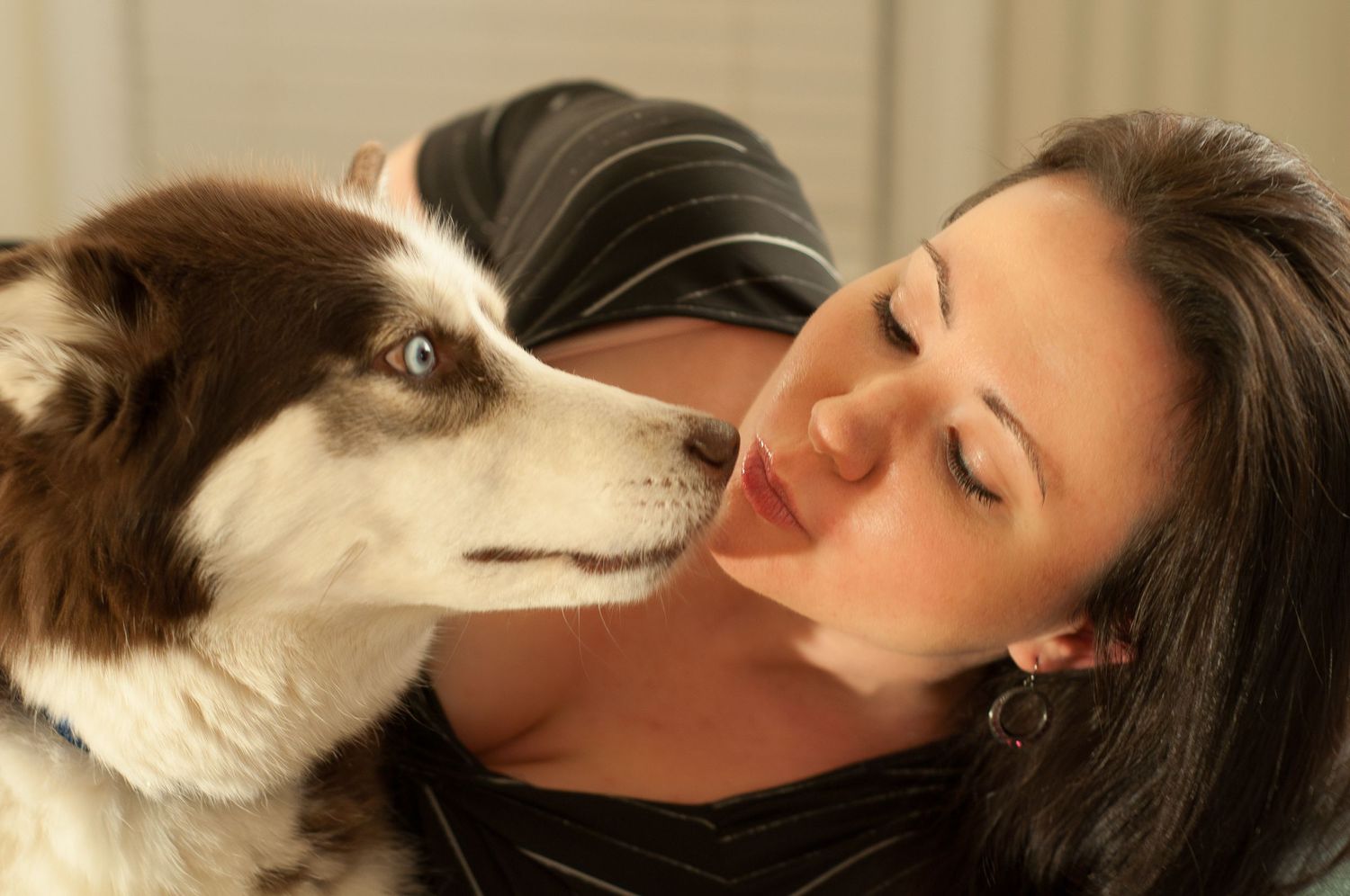Portrait of smoking hot woman posing with her Siberian husky. She's making a kissy face next to the husky.