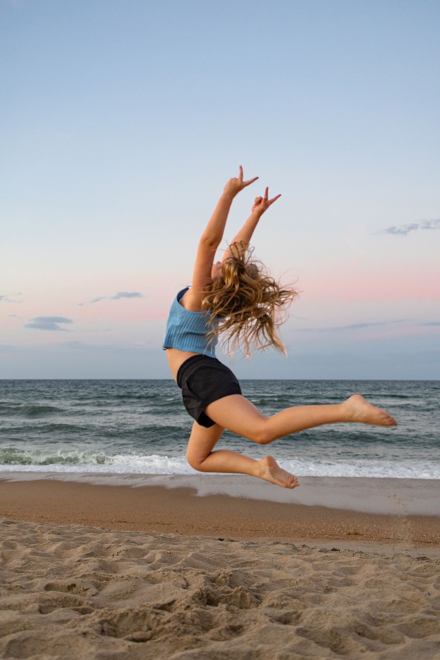 Portrait of an athlete leaping on the beach with a sunset