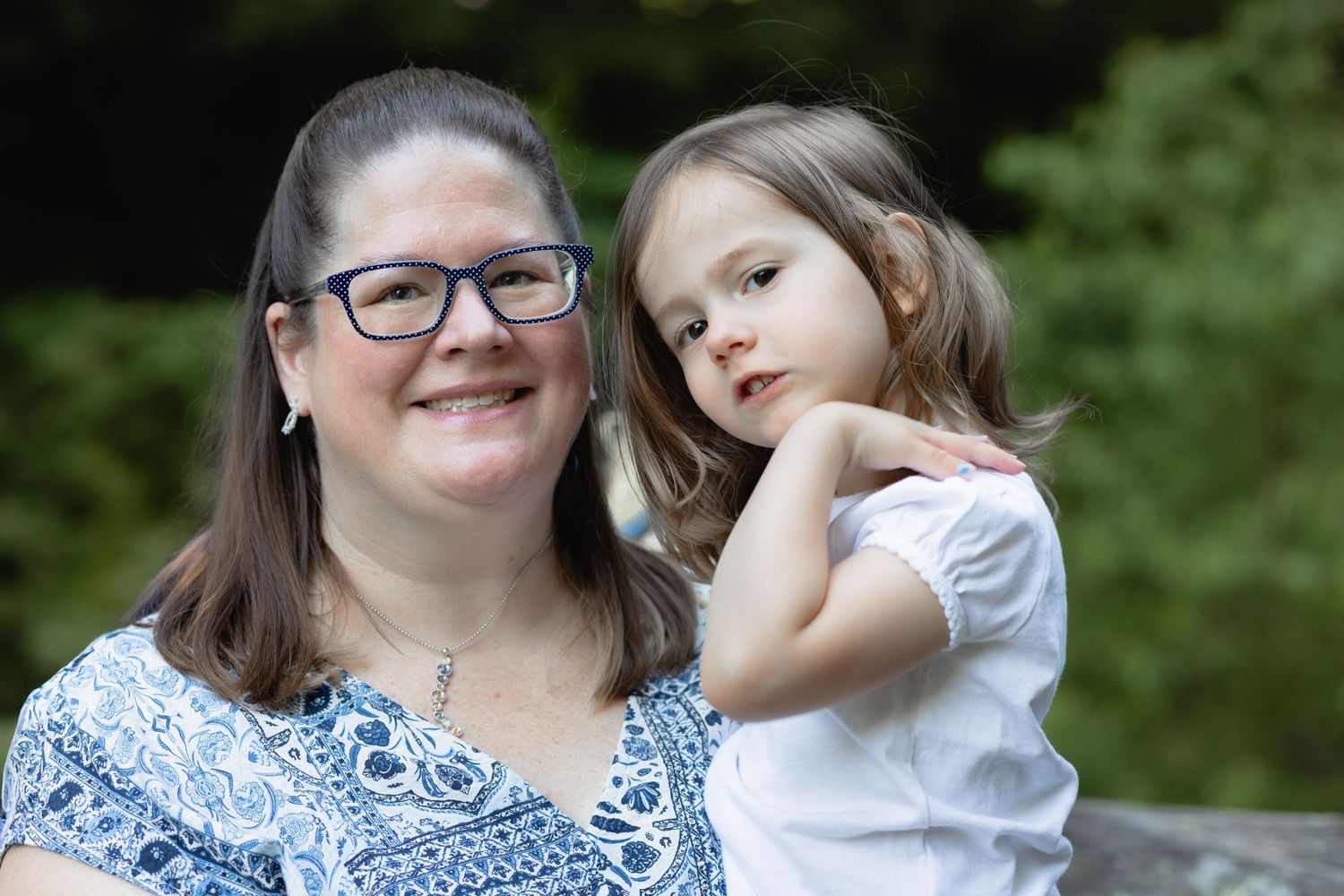 Portrait of a woman wearing glasses and a blue and white dress holding a child