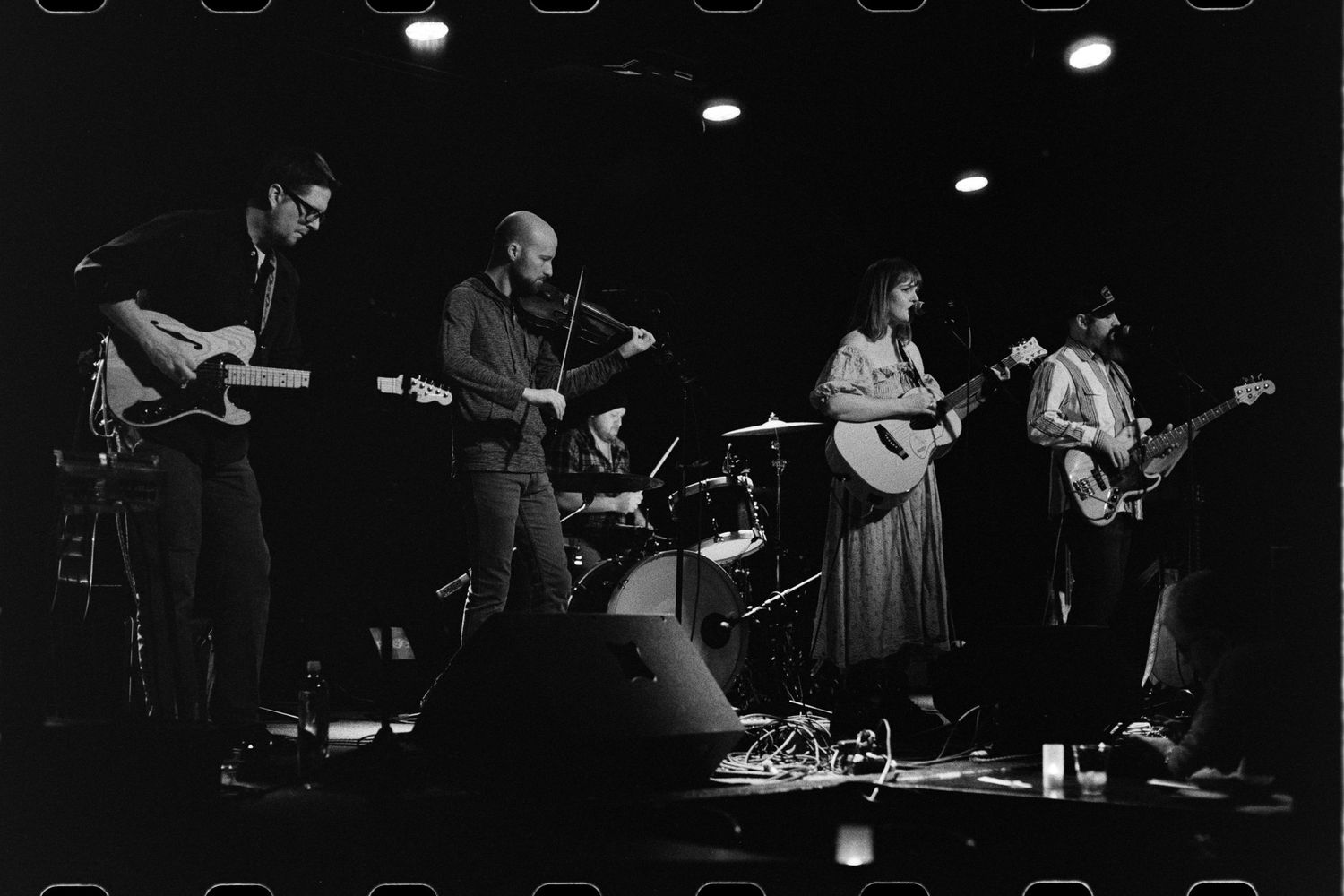 Black & white photos of a five-piece country band playing on stage.