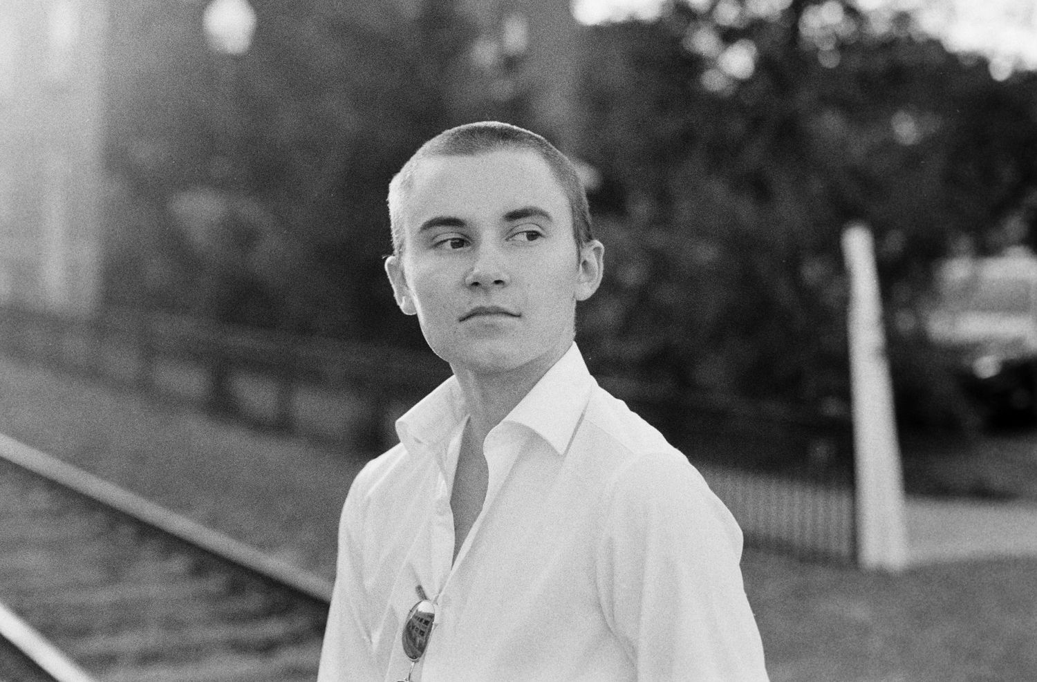 Black & white portrait of a young man looking to his left wearing a white button-up shirt.