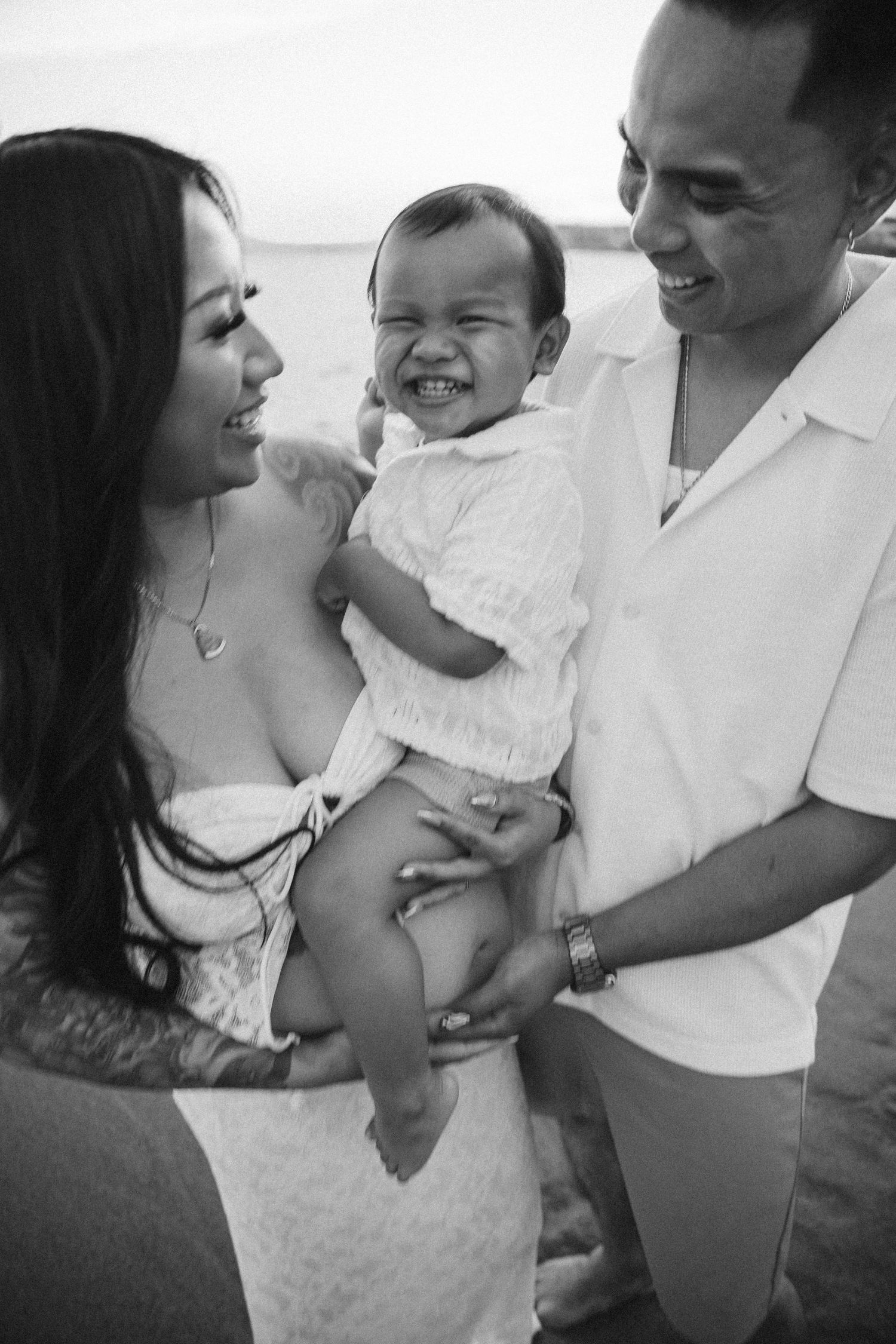 Black and white candid photos capture tender family moments on the beach during a lifestyle session.