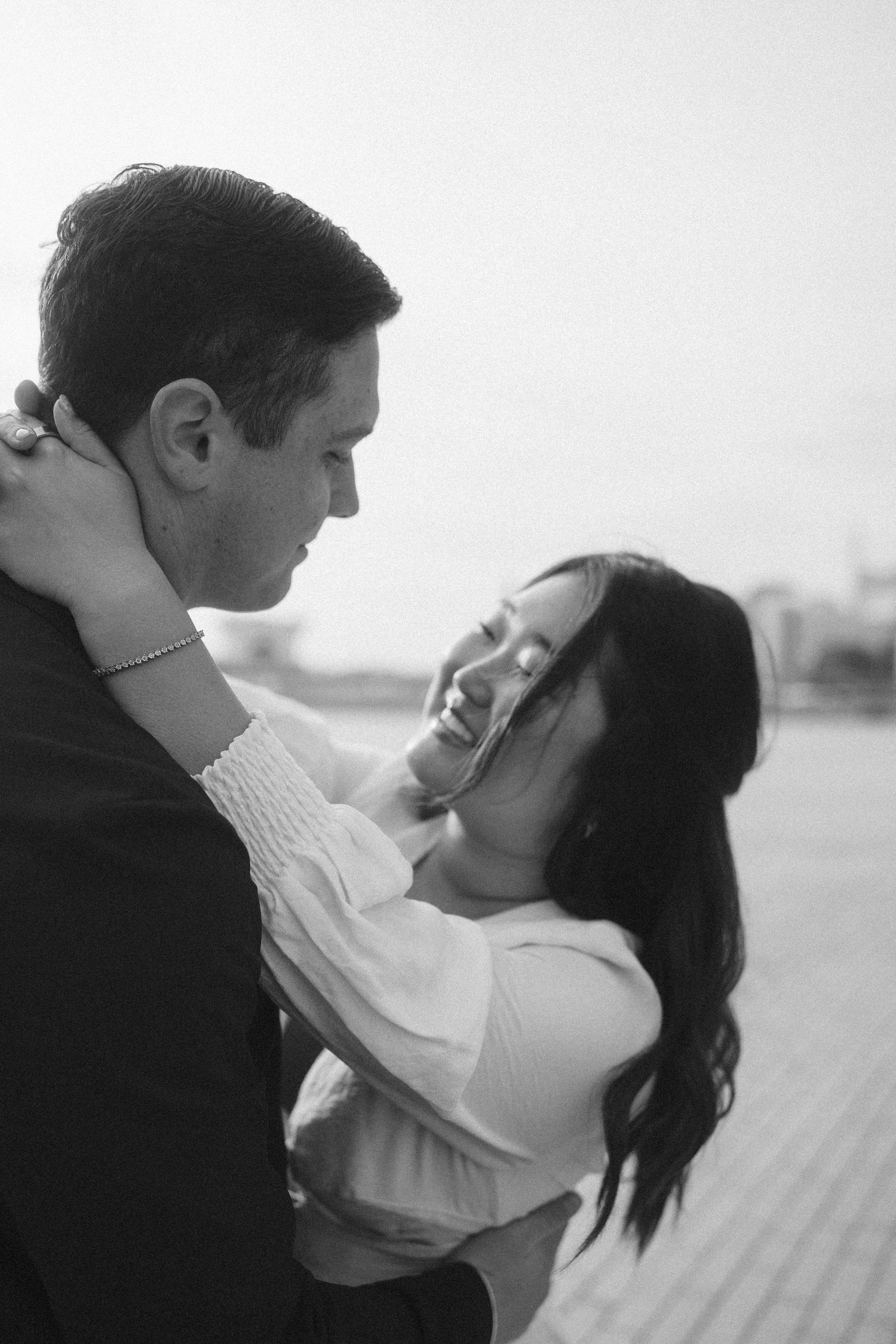 A romantic black and white photo of a couple embracing and laughing together in an intimate moment.