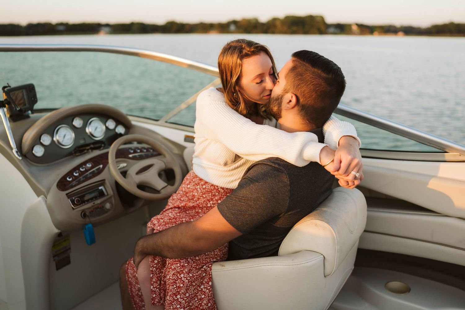 Couple sharing an intimate moment while sitting in a boat at sunset on calm waters.