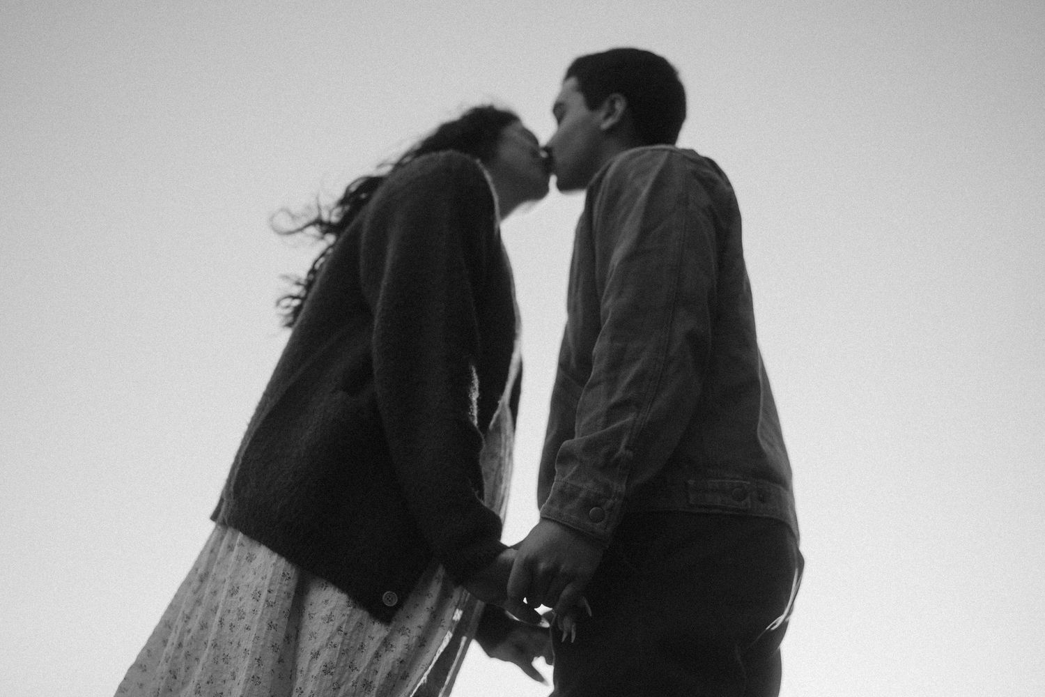 An intimate black and white portrait of a couple sharing a tender moment outdoors.