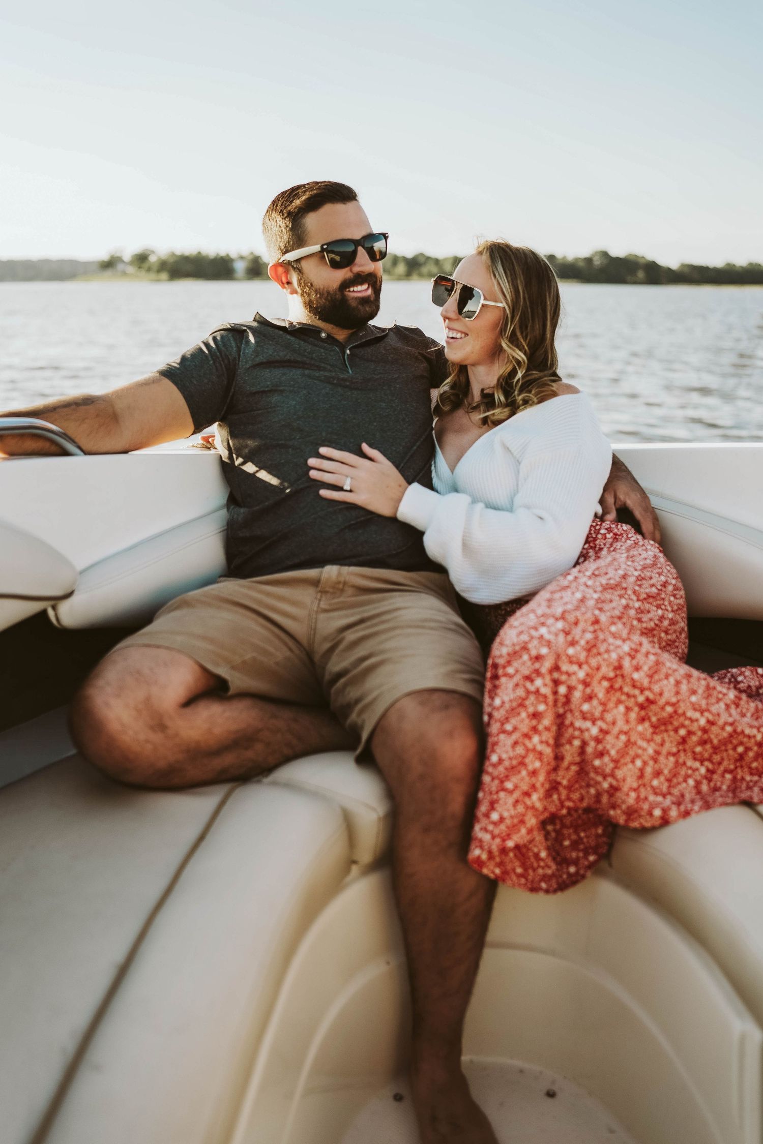 Couple relaxing together on a boat enjoying a sunny day on the water with sunglasses and casual summer attire.