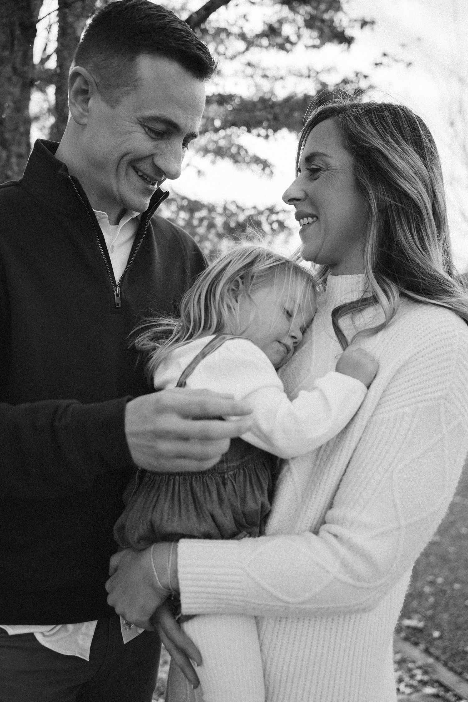Black and white intimate portraits of a couple embracing with their newborn baby in a tender moment.