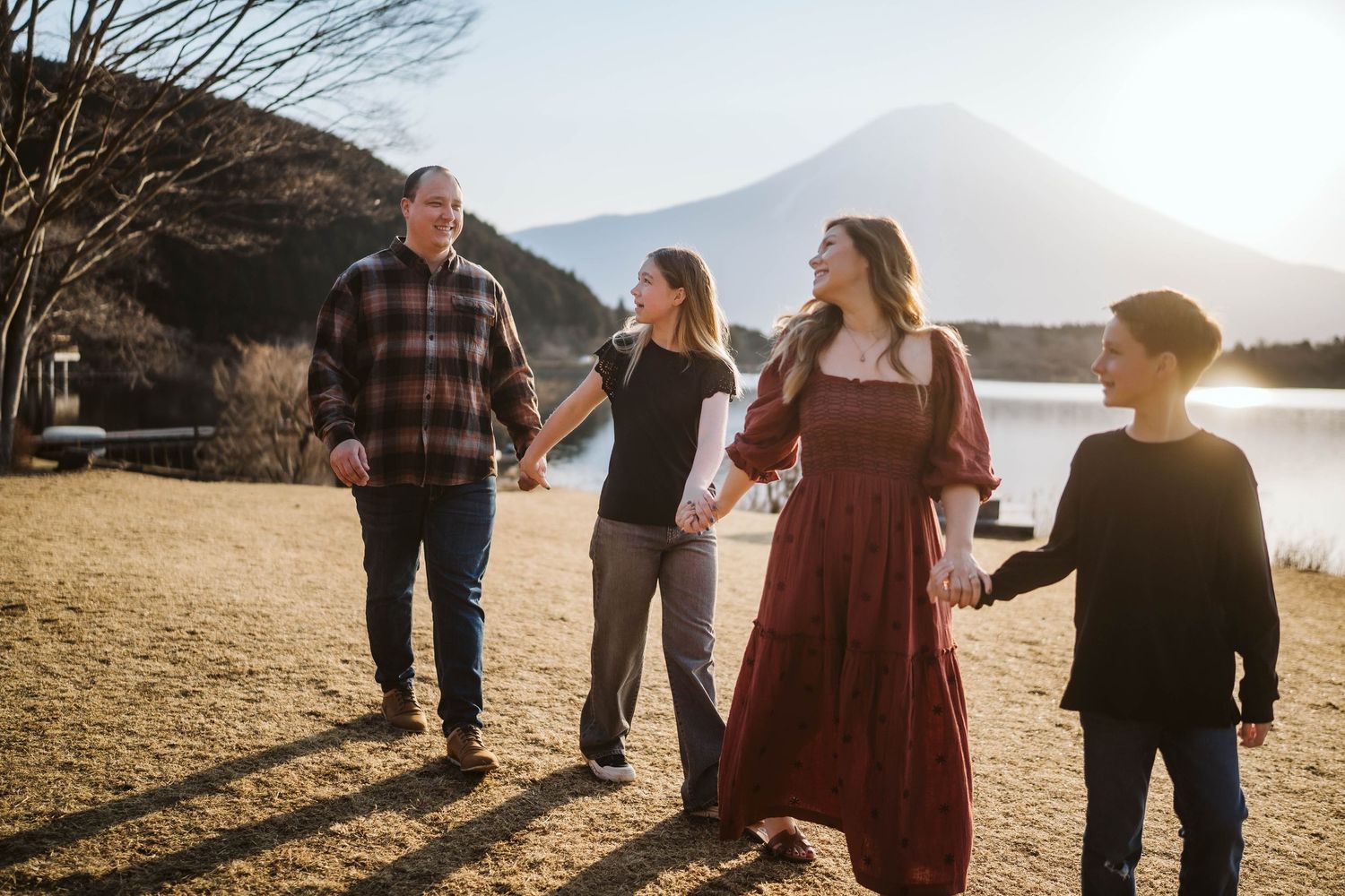 A group of people walking together outdoors against a scenic mountain landscape during golden hour at a lake.