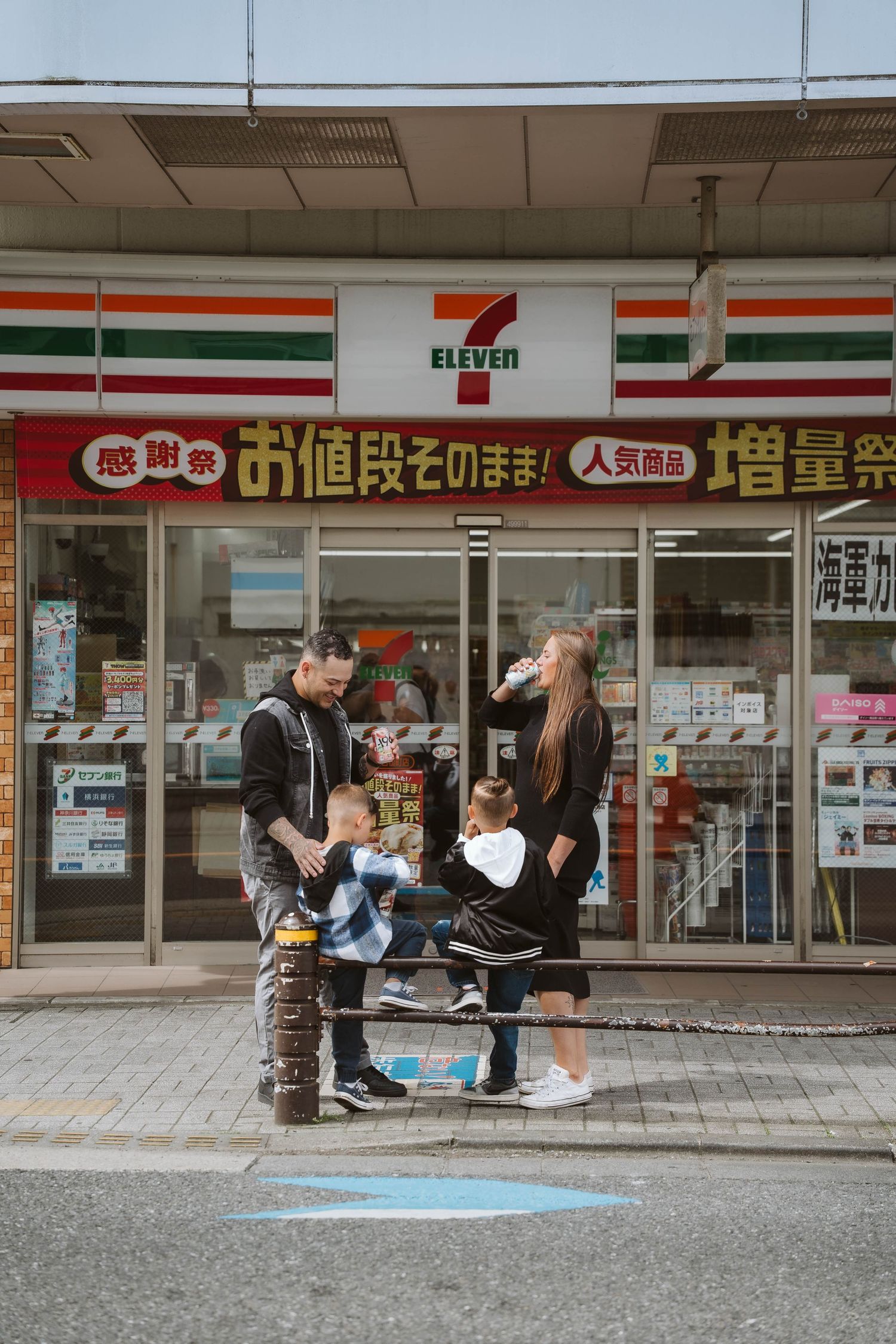 People gathered outside a 7-Eleven convenience store in Japan with promotional signage.