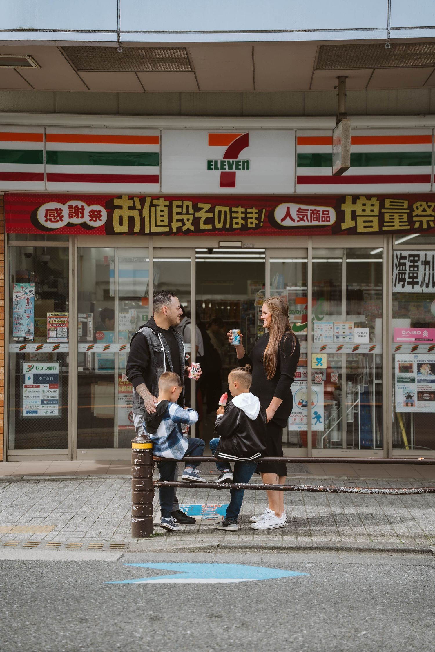Group gathered outside a Japanese convenience store with storefront signs and vending machines.