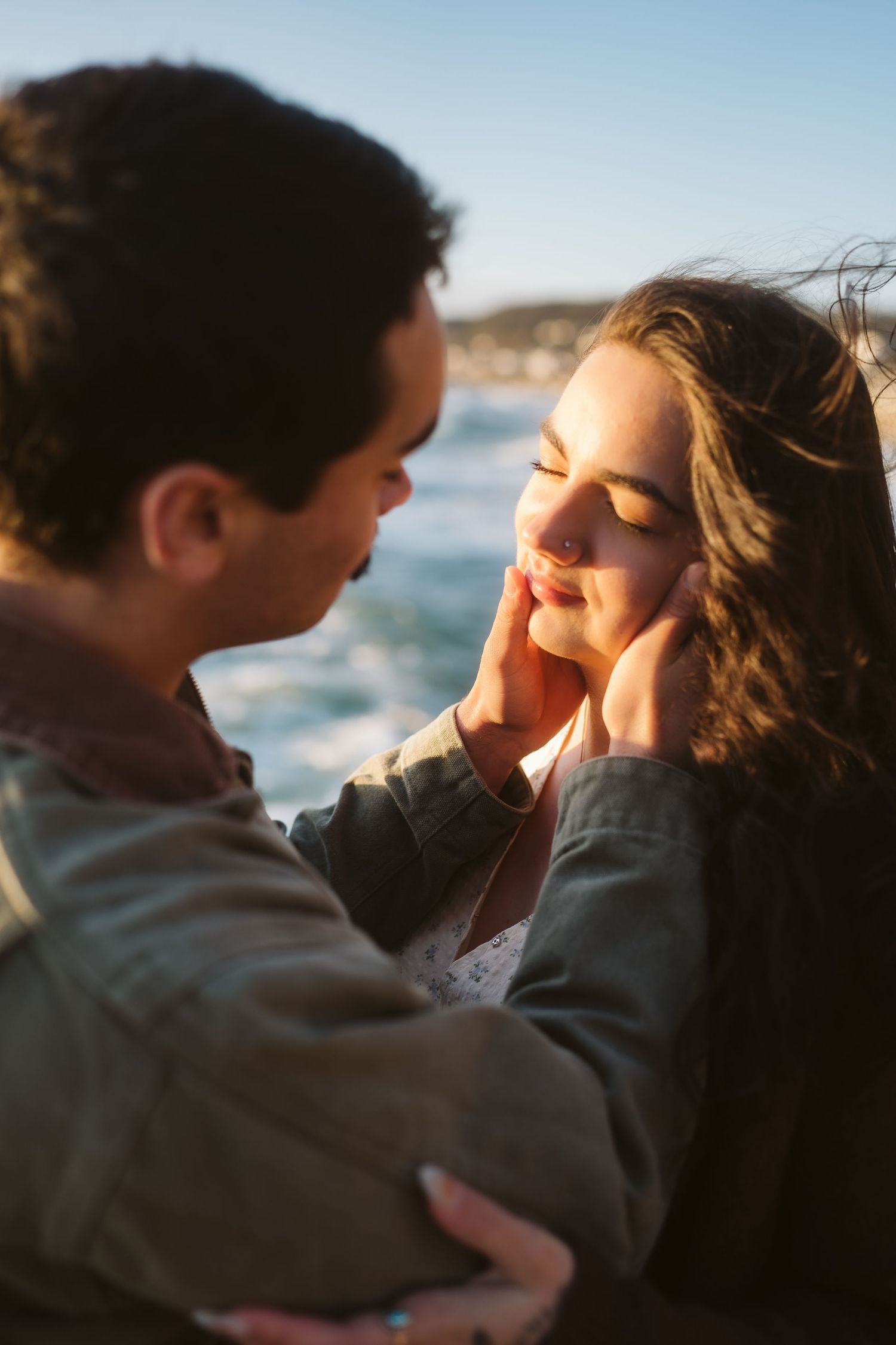 Romantic couple shares intimate moments by the ocean at sunset in a series of tender close-up photographs.