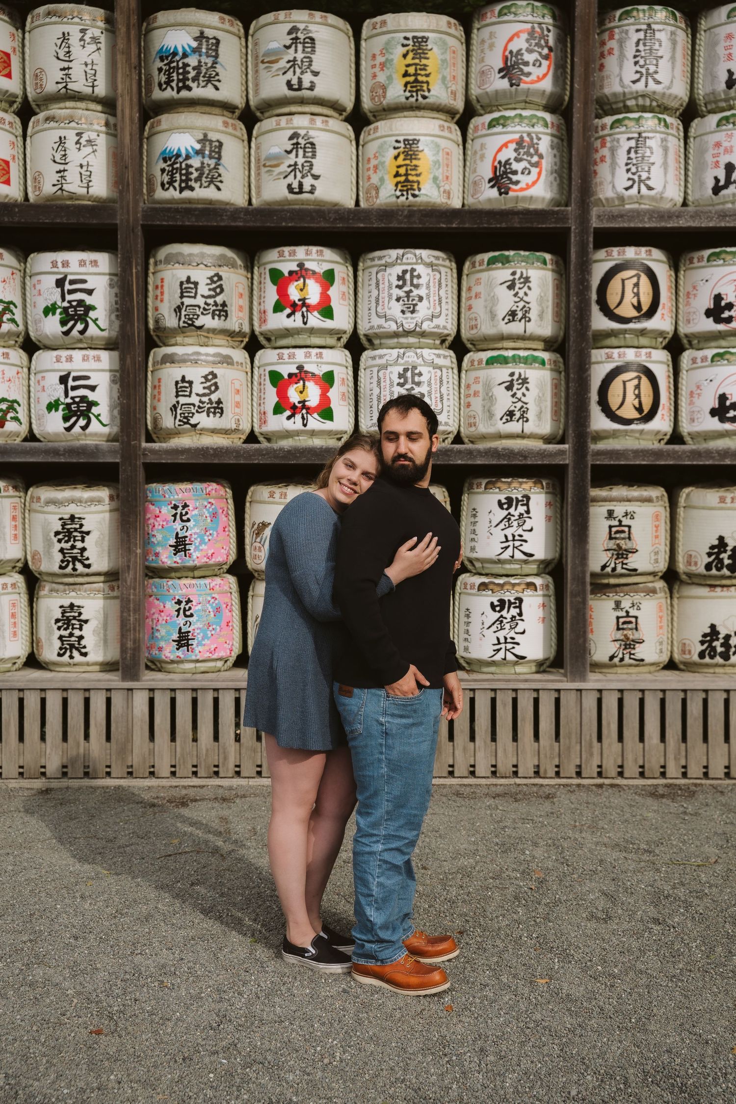 Traditional sake barrels with Japanese calligraphy stacked at a shrine display.
