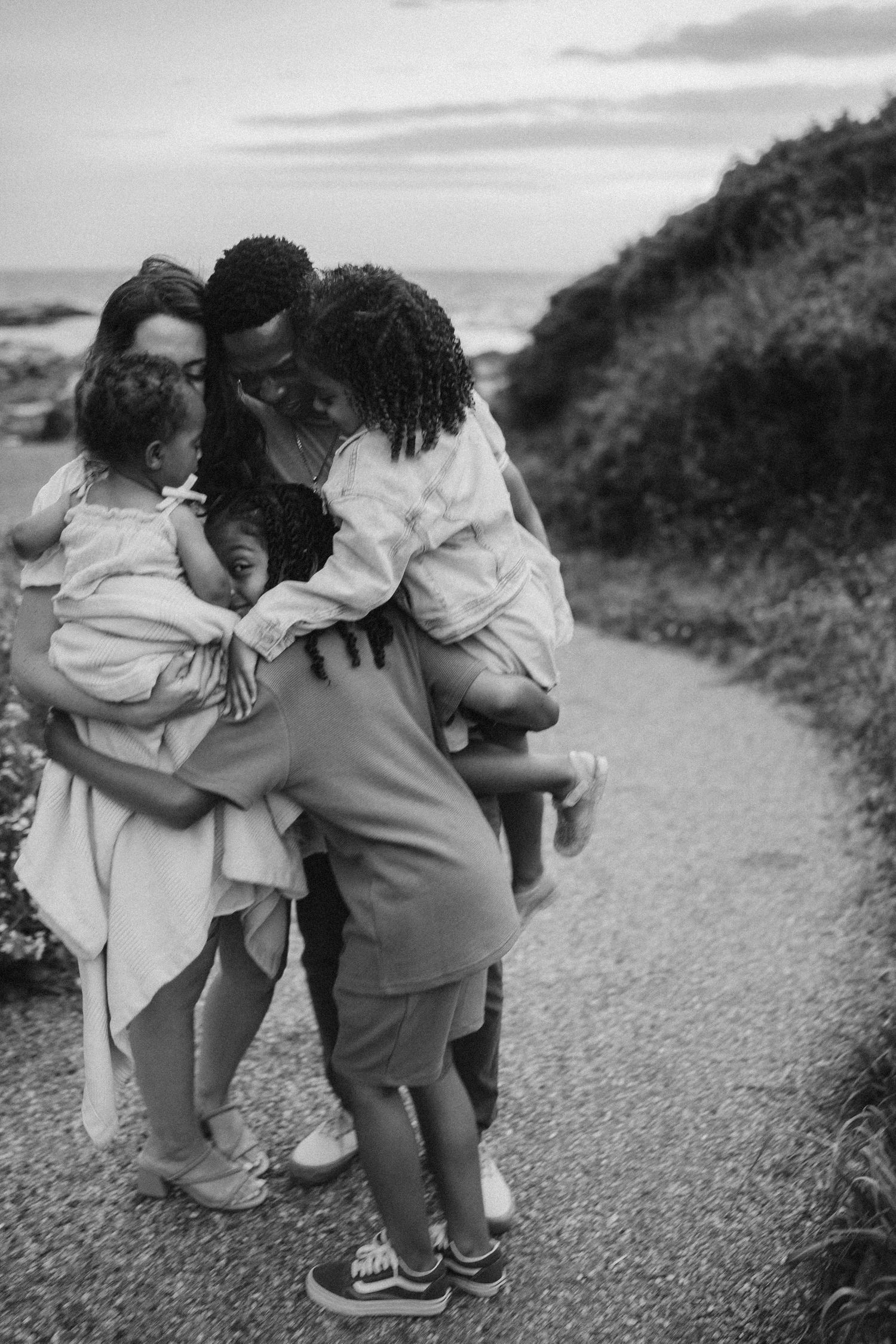 A touching black and white family moment captured on a gravel path surrounded by nature.