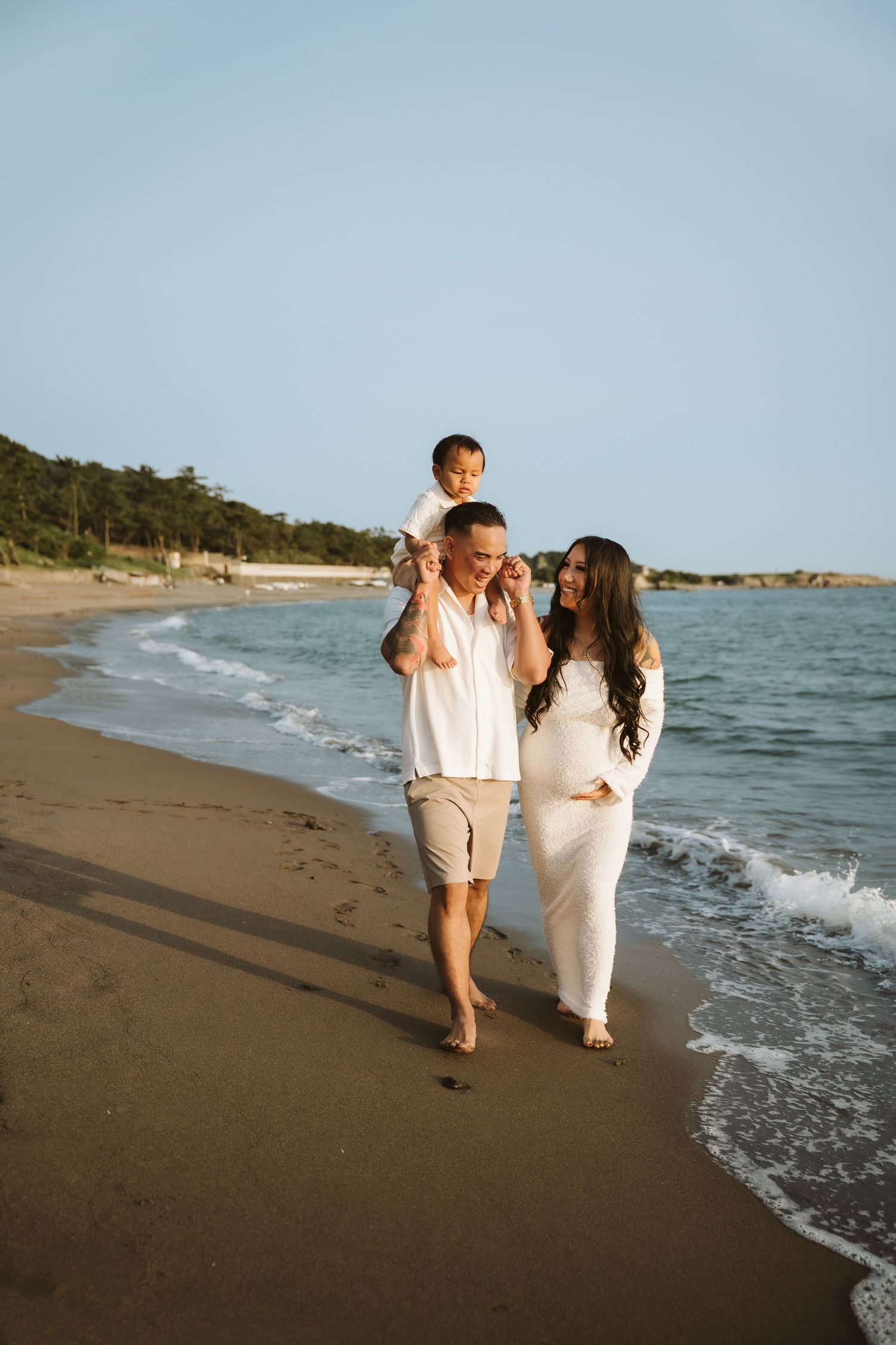 A romantic couple walks along the shoreline of a beach with waves crashing nearby.