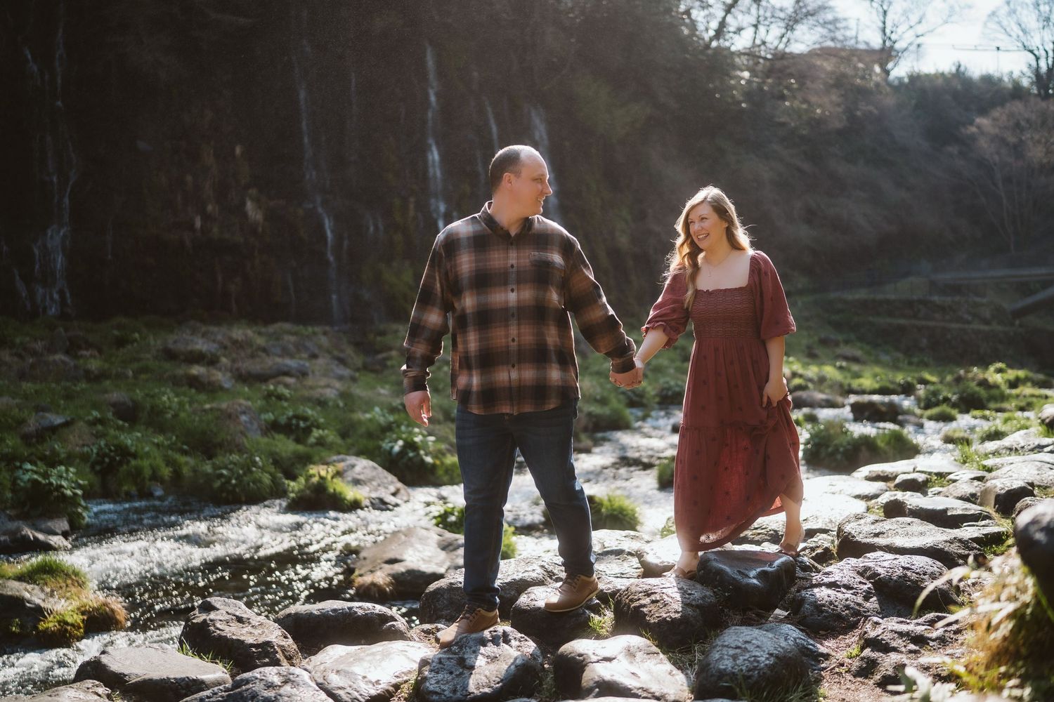 Two people walk together along a scenic rocky stream on an autumn afternoon in nature.