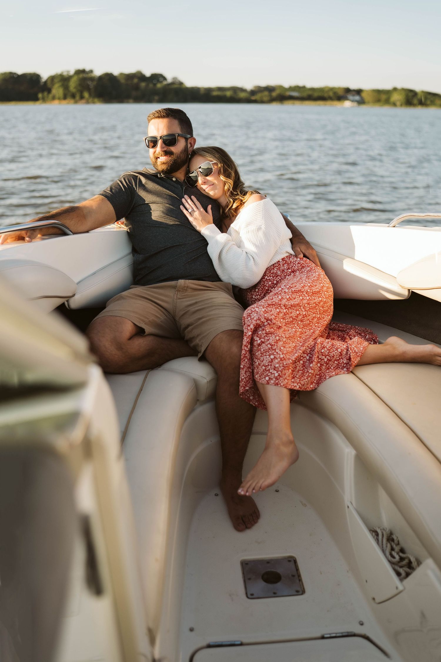 A couple relaxes together on cushioned boat seating while enjoying a sunny day on the lake.