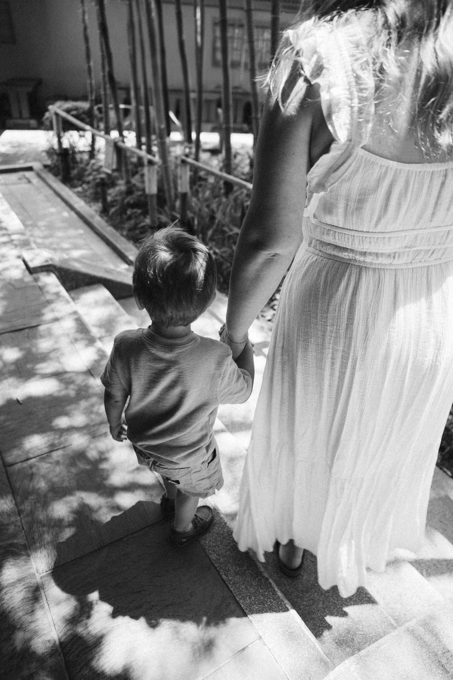 Black and white photo of a couple sharing an intimate moment in a sunlit outdoor setting.