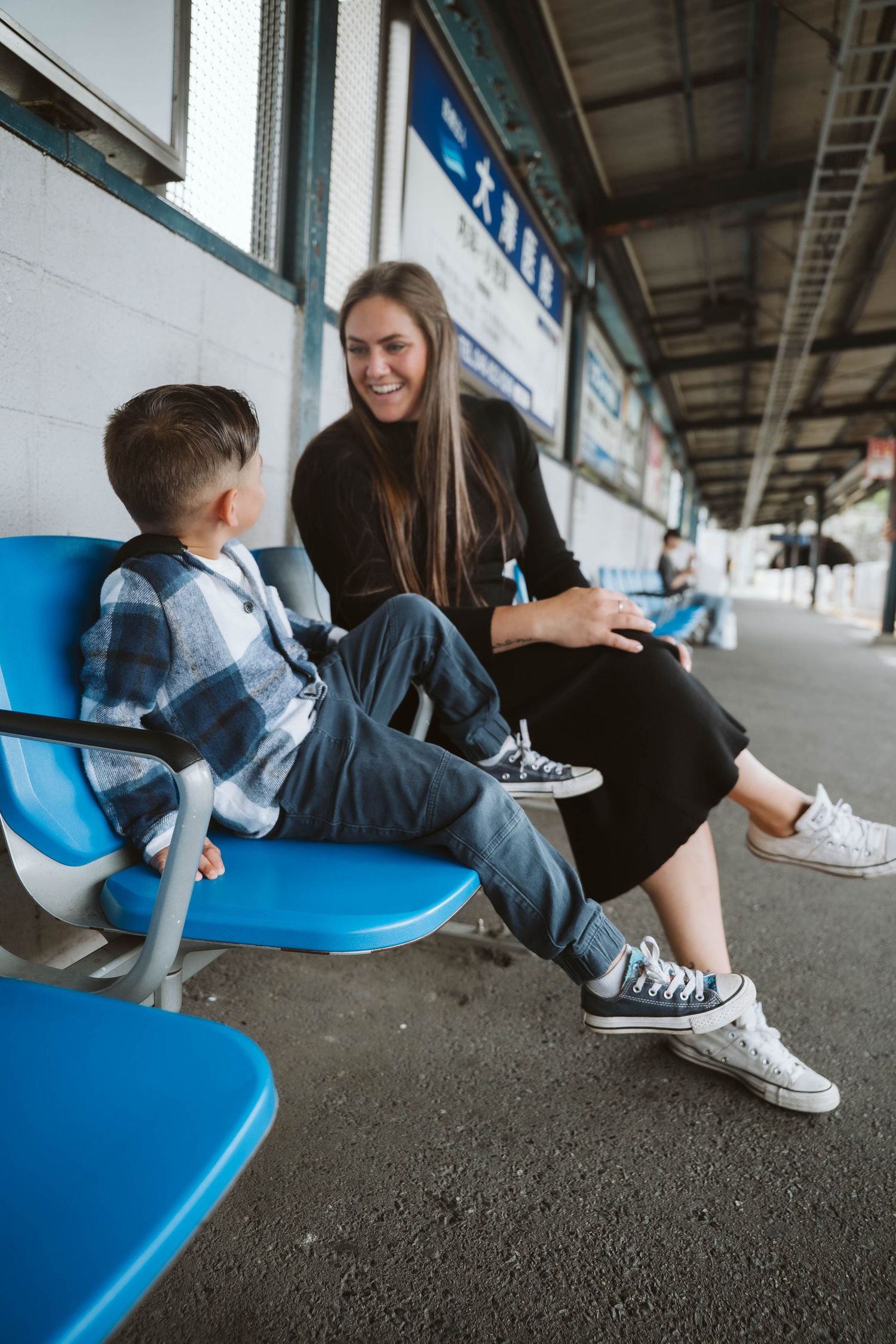 People sitting on bright blue seats at what appears to be a train or subway platform.