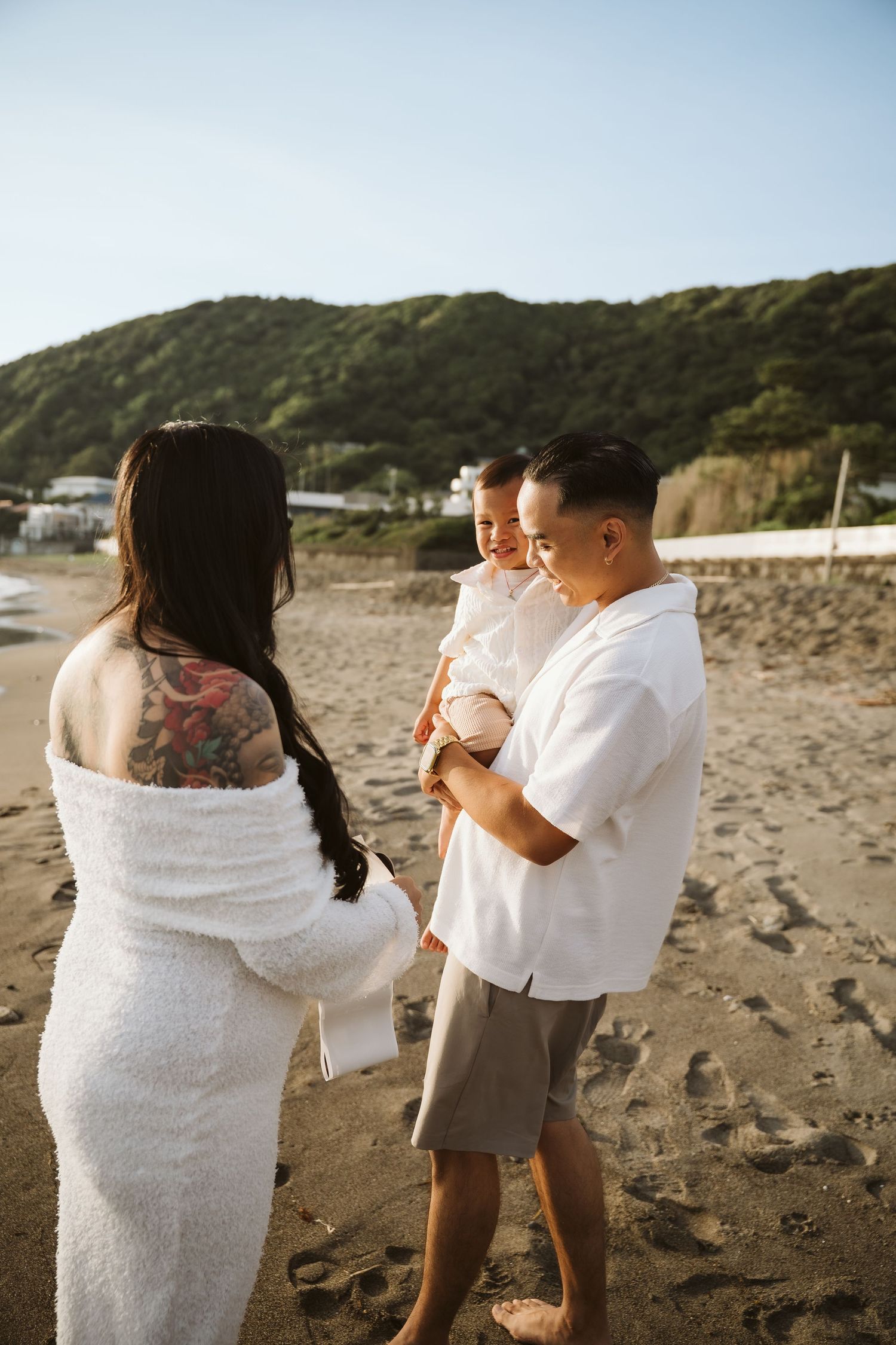 A couple embraces while dancing together on a sandy beach at sunset.