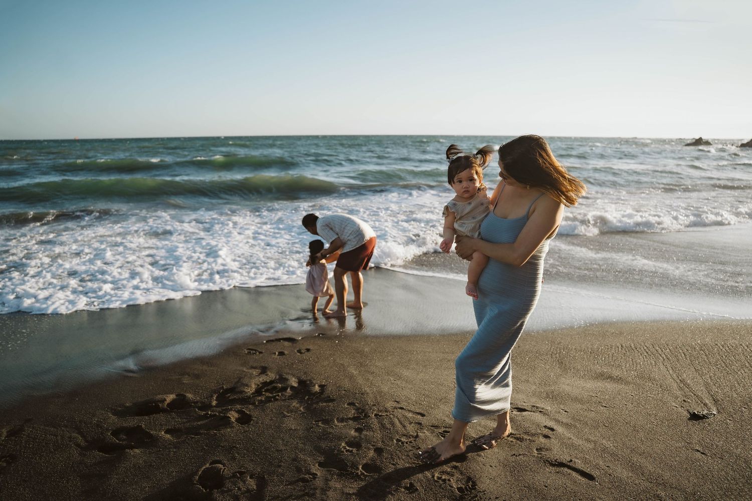 People enjoy quality time together on a dramatic black sand beach with rolling ocean waves.