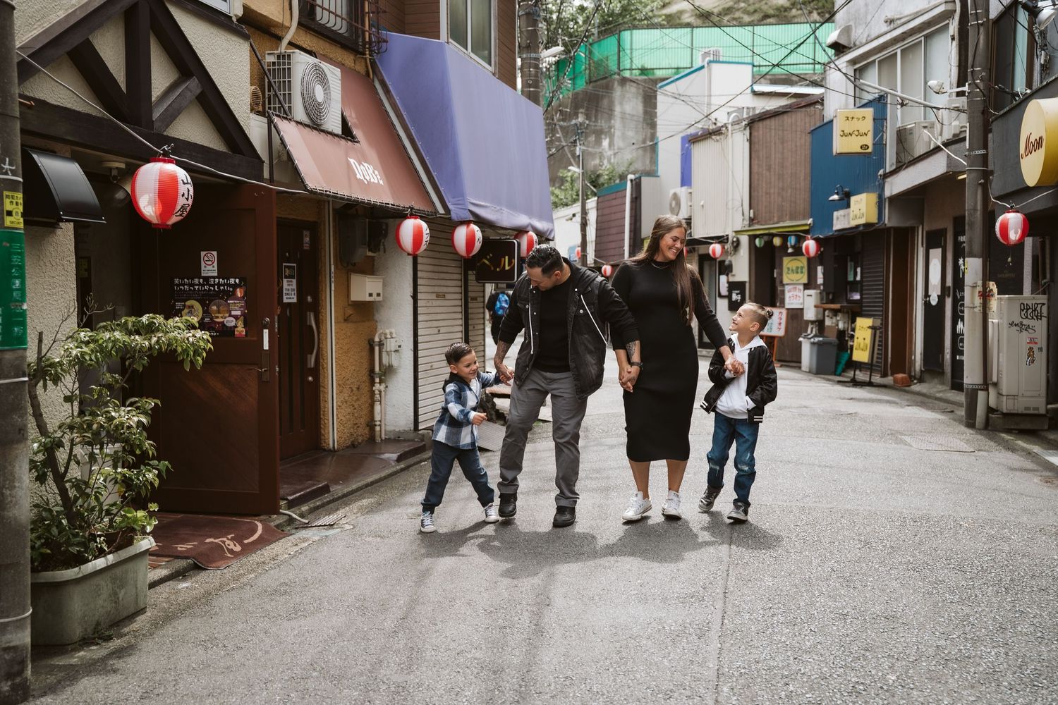 Pedestrians walk along a narrow cobblestone street lined with traditional Japanese lanterns and shops in Kyoto.