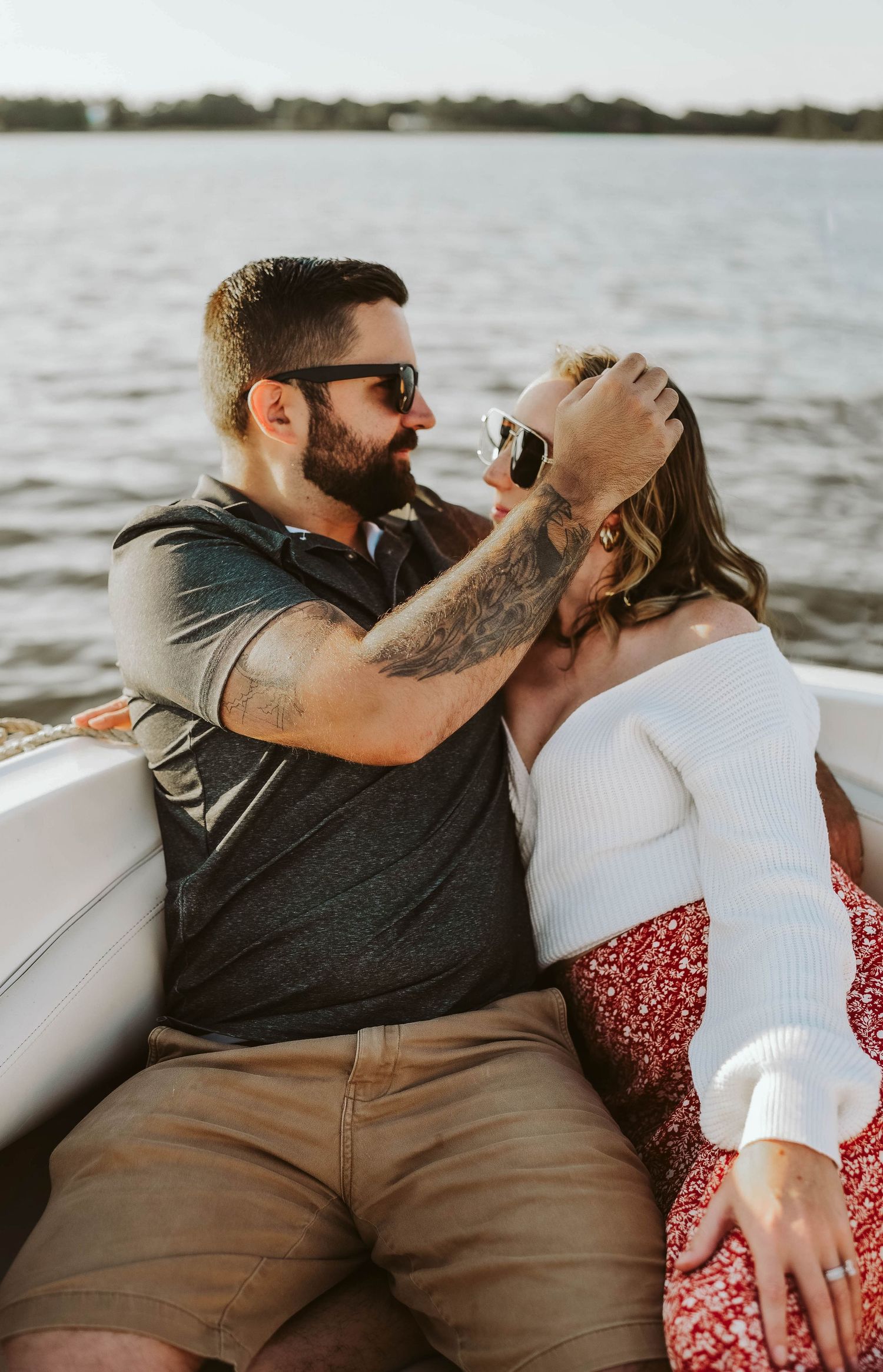 Romantic couple shares an intimate moment while sitting on a boat at sunset by the water together.