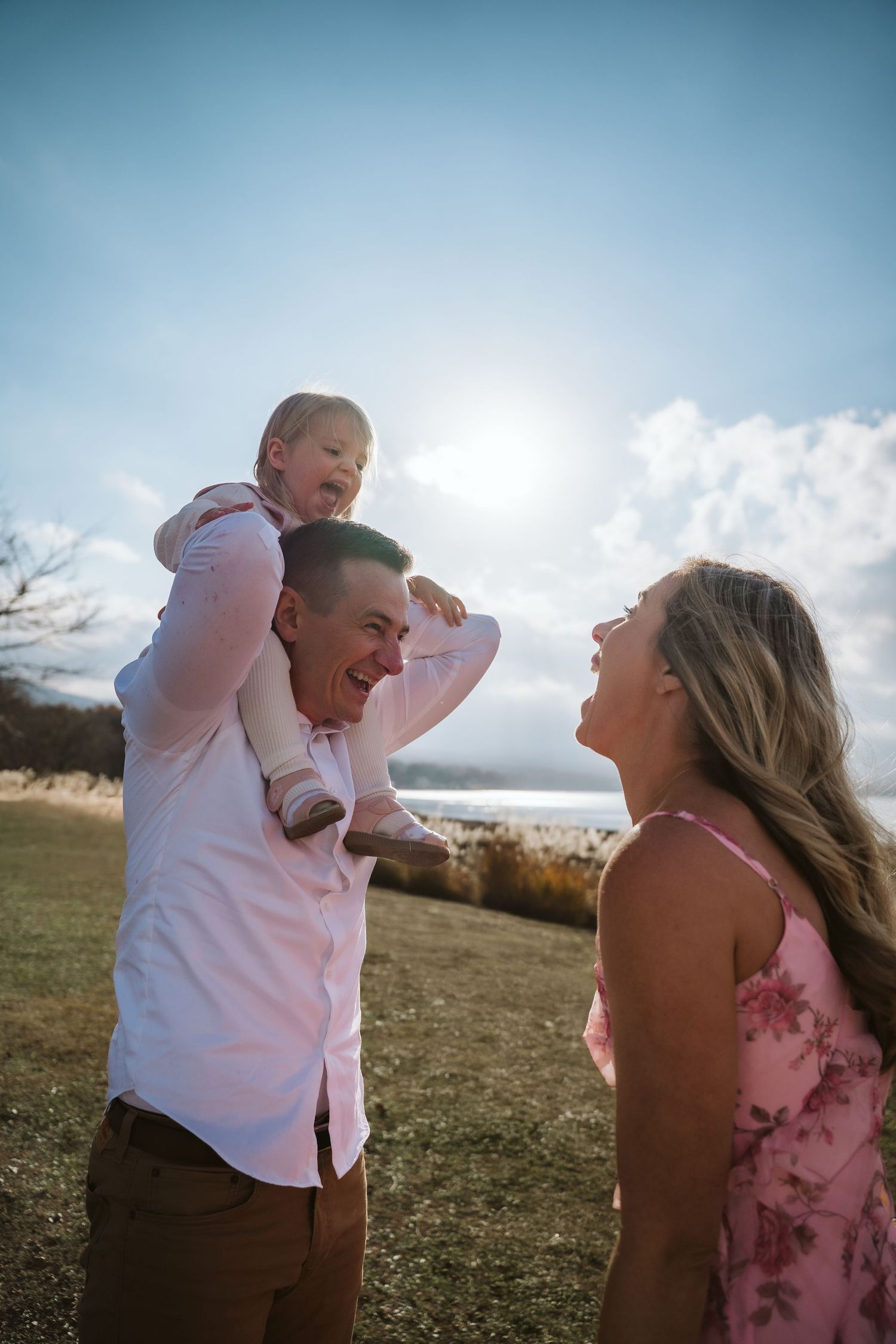 A couple shares joyful laughter together in a series of candid outdoor photos at sunset in a grassy field.