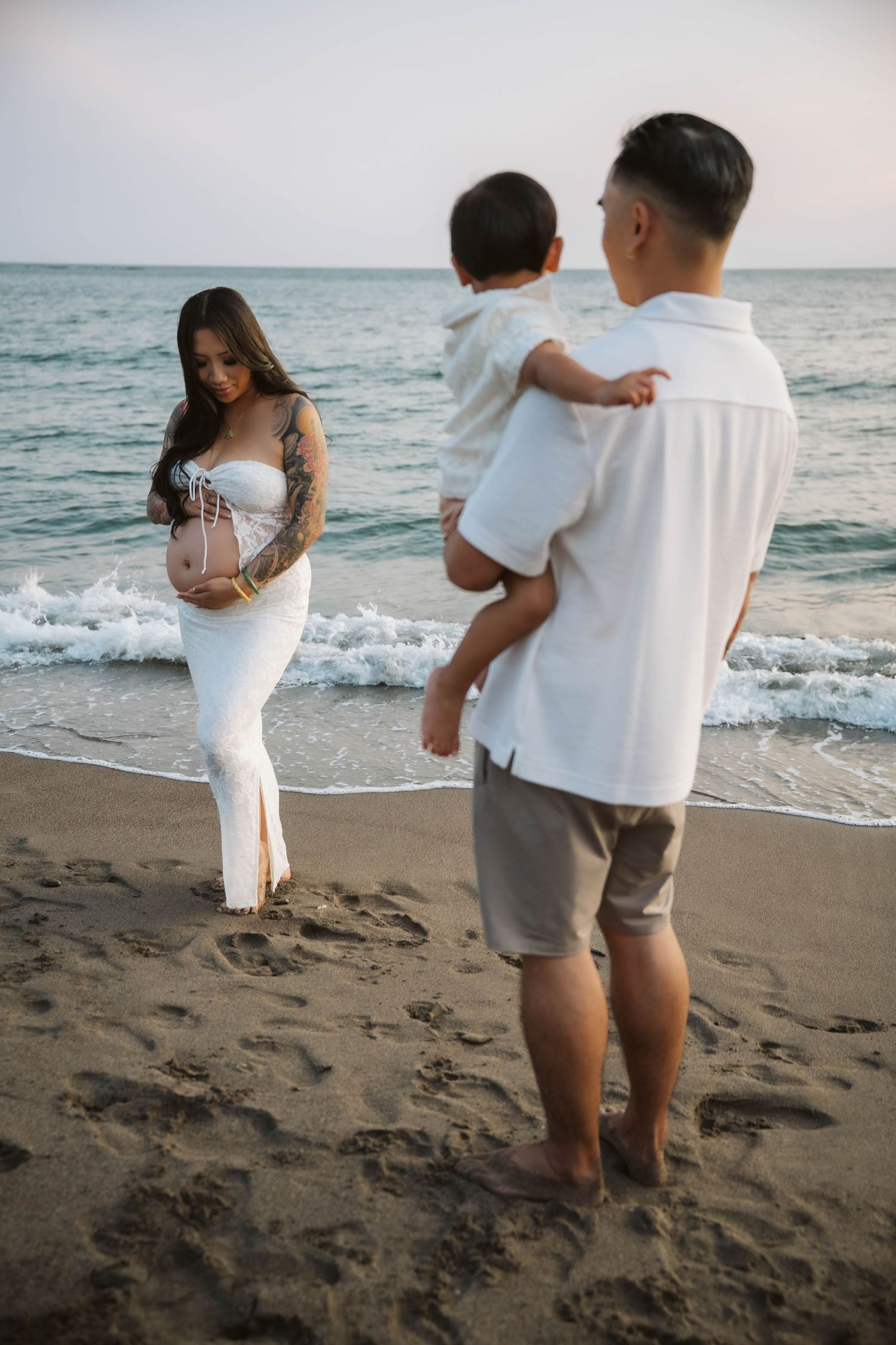 Family enjoying a sunset beach moment together with waves crashing on the shore behind them.
