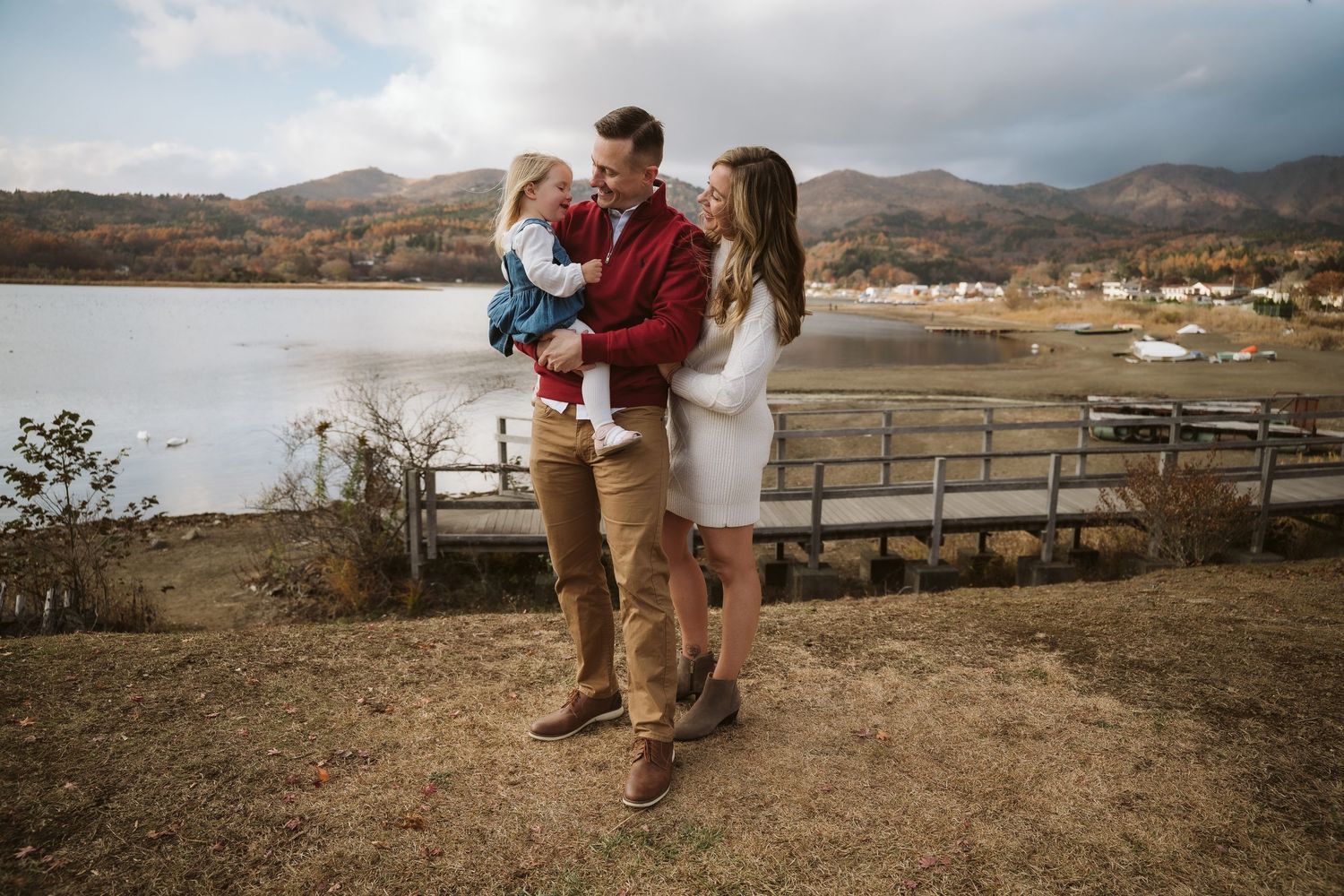 A couple shares a romantic moment overlooking a scenic mountain lake during sunset.