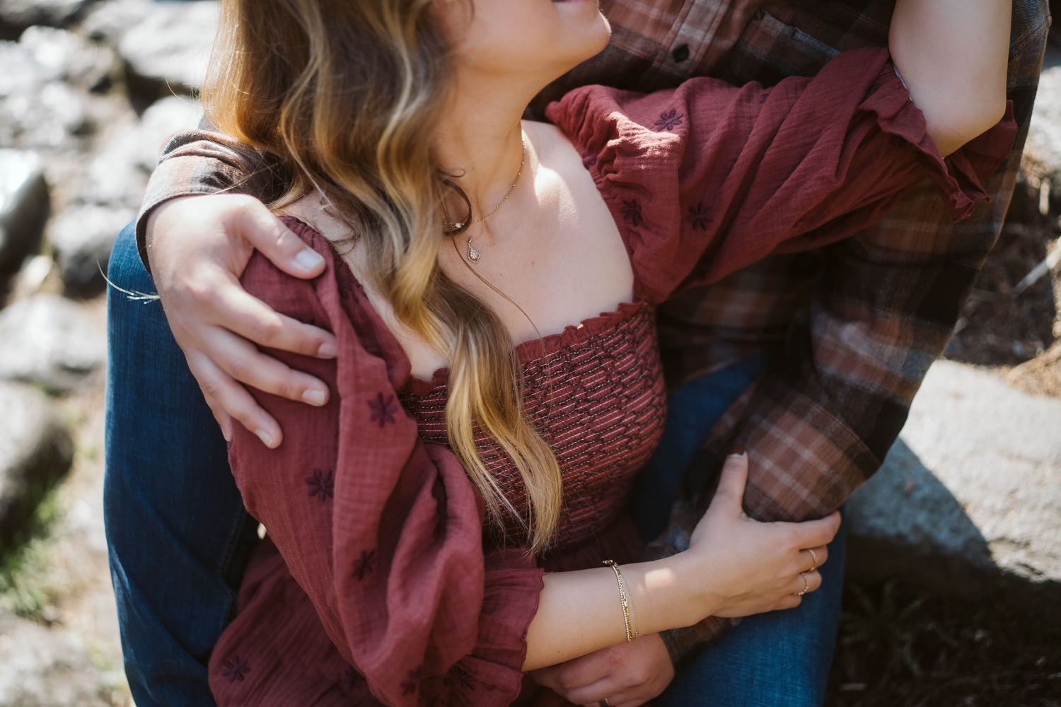 Romantic couple in burgundy and plaid clothing share intimate moments during an outdoor photo session.