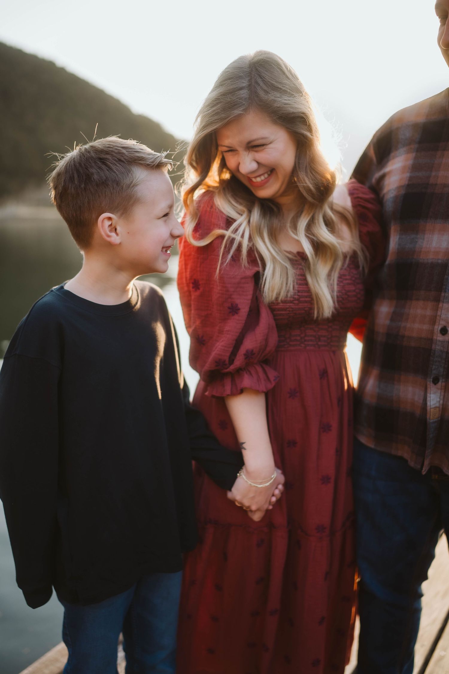 A joyful family moment captured at sunset by the water with warm golden light.