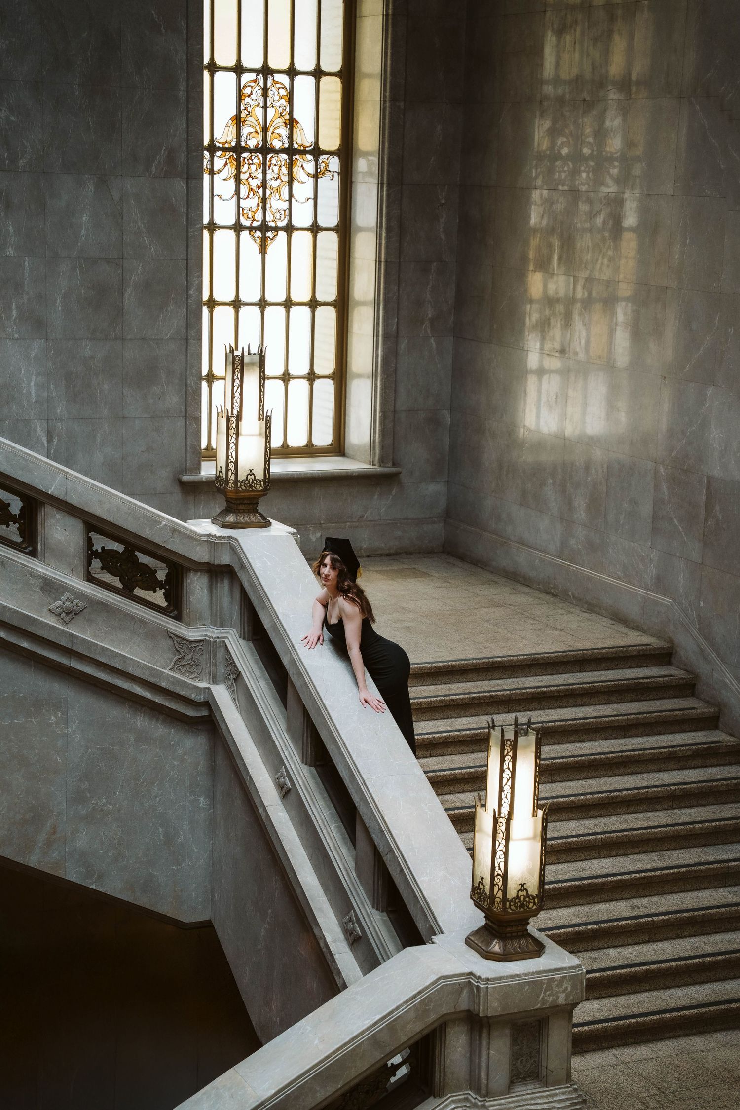Elegant stone staircase with ornate railings and windows in a classical architectural setting.