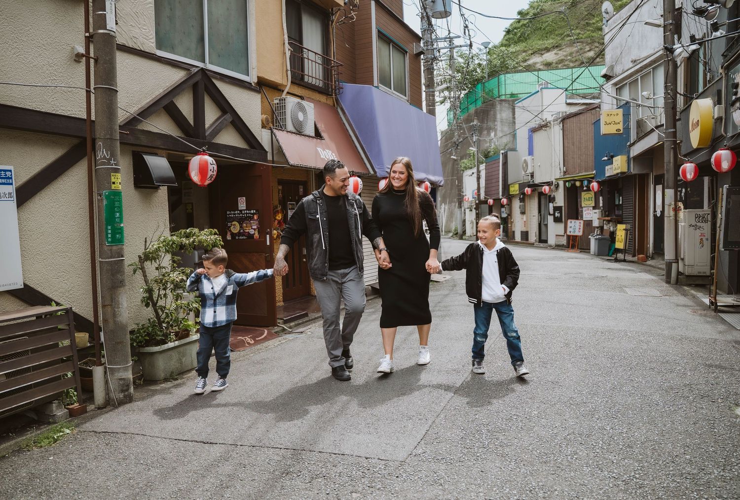 Tourists exploring a quaint Japanese street lined with traditional buildings and lanterns.