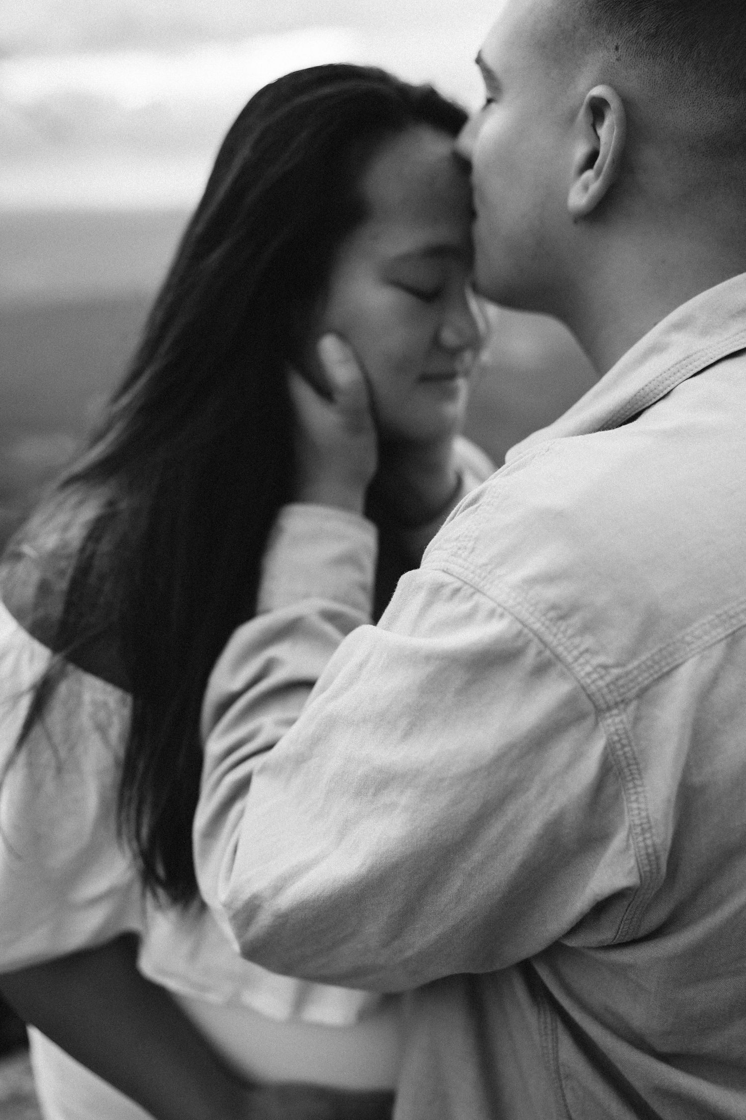 A tender black and white close-up of an intimate embrace between a couple sharing a romantic moment.